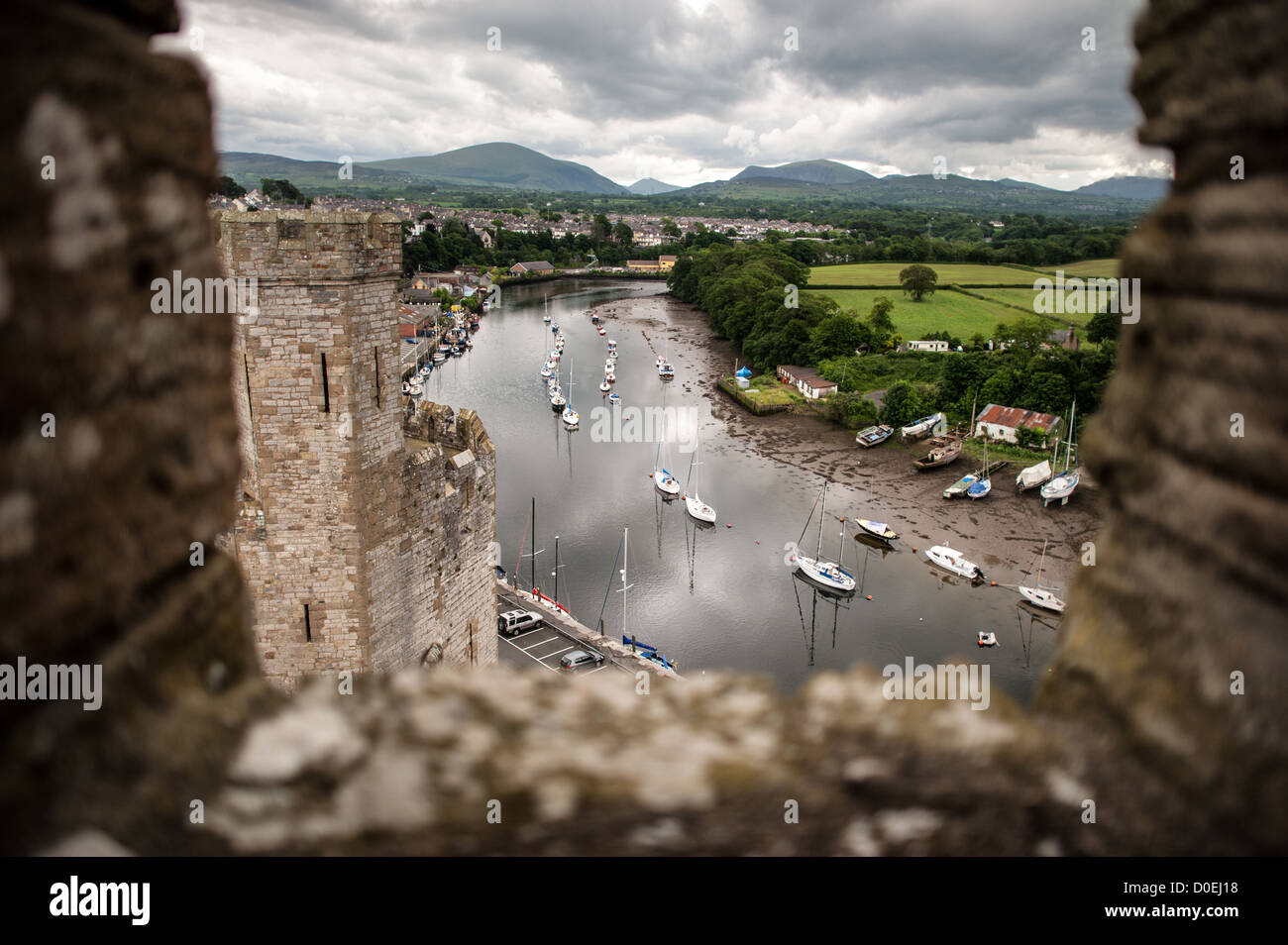 CAERNARFON, Pays de Galles - bateaux amarrés sur le fleuve loin ci-dessous comme vu du haut d'une des tours au château de Caernarfon distinctif dans le nord-ouest du pays de Galles. Un château s'élevait à l'origine sur le site remontant à la fin du xie siècle, mais à la fin du 13e siècle, le Roi Edward J'ai commandé une nouvelle structure qui se tient à ce jour. Il possède des tours et est l'un des mieux conservés de la série de châteaux-QUE J'ai commandé. Banque D'Images