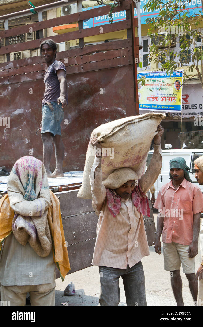 Décharger un camion de travailleurs avec des sacs de ciment à Mumbai, Inde Banque D'Images