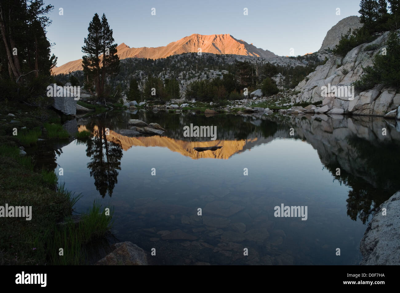 Encore un lac de montagne près de coucher du soleil à la réflexion d'arbres et montagne lointaine Banque D'Images