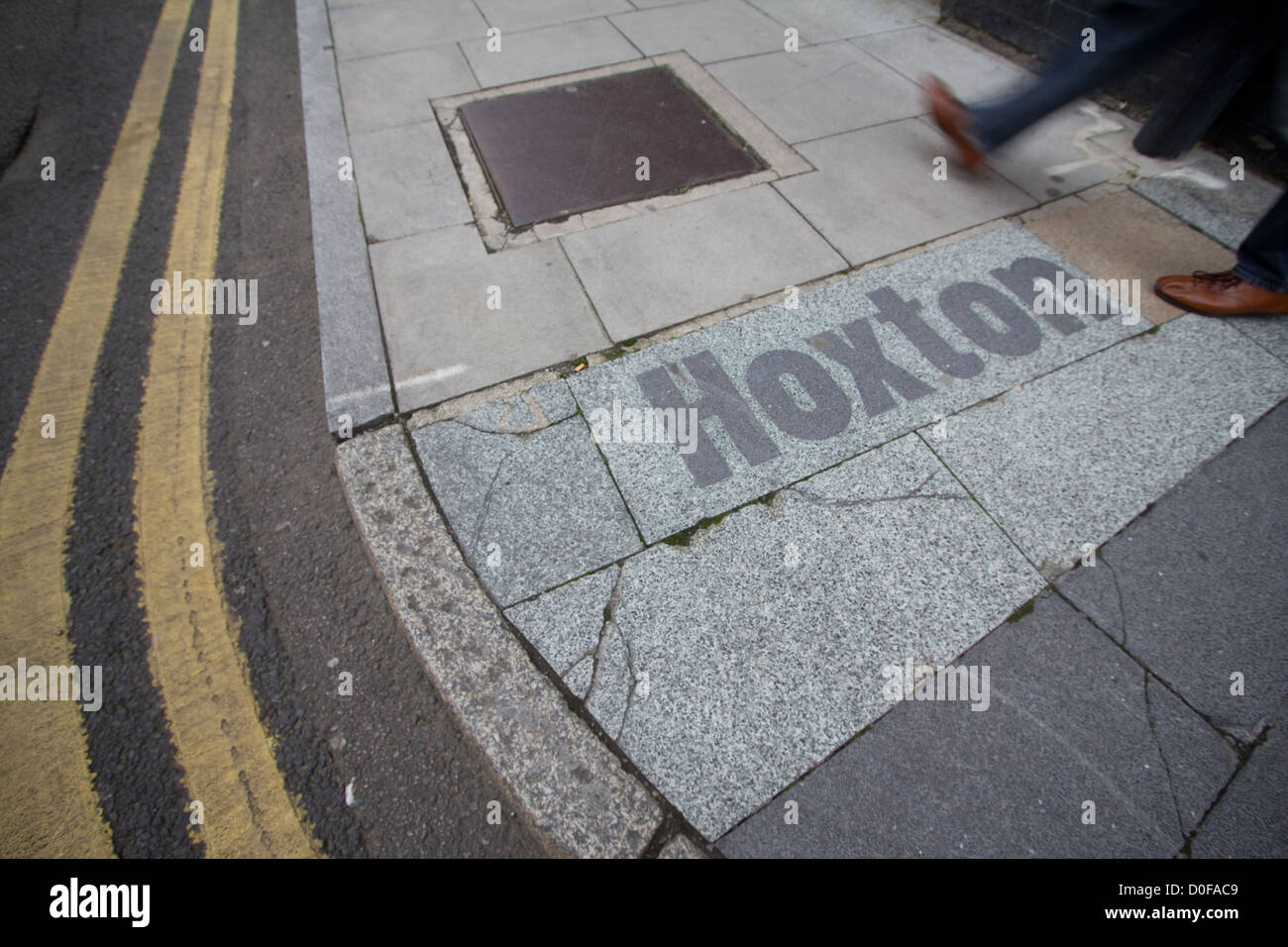 Un homme marche sur un panneau de trottoir à Hoxton, Londres, Royaume-Uni, ajoute du caractère au paysage urbain dynamique de l'est de Londres, reflétant le mélange d'industries créatives, d'entreprises indépendantes et de culture urbaine de la région Banque D'Images