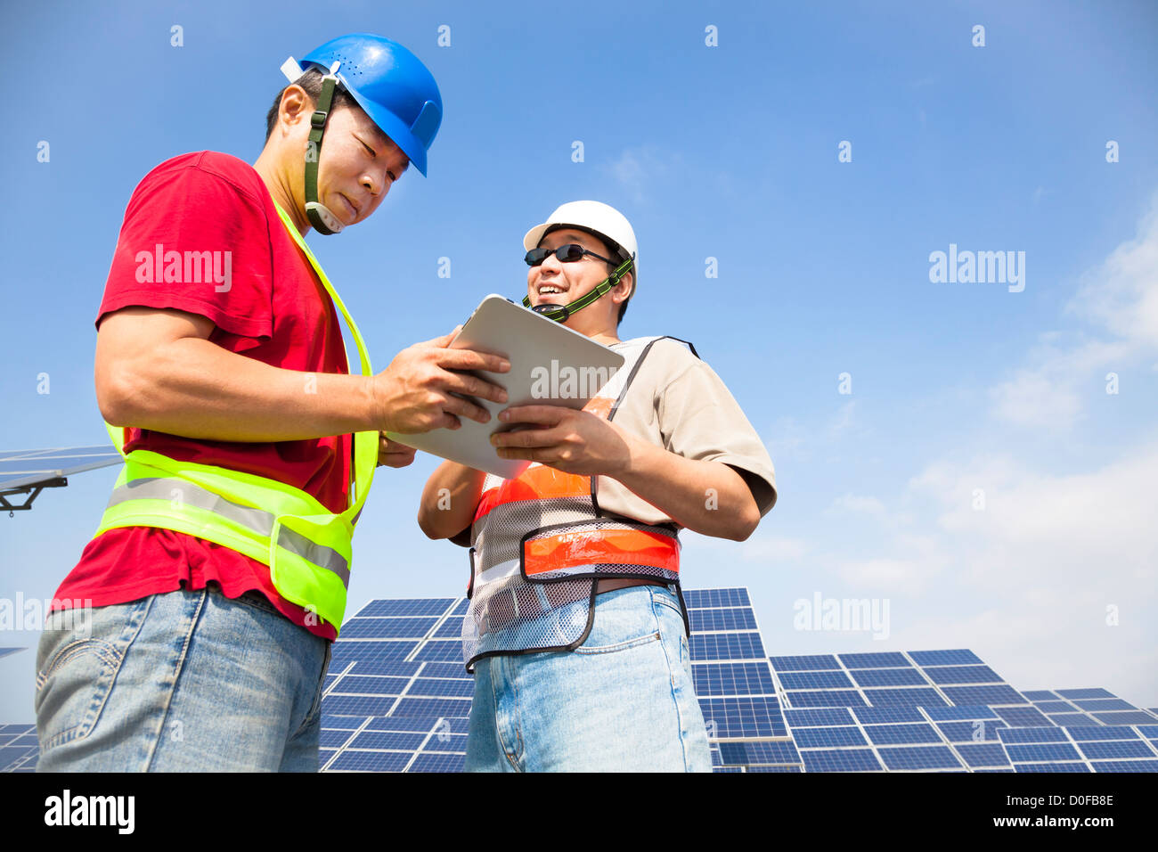 Deux travailleurs discutant avec tablet pc avant la station d'énergie solaire Banque D'Images