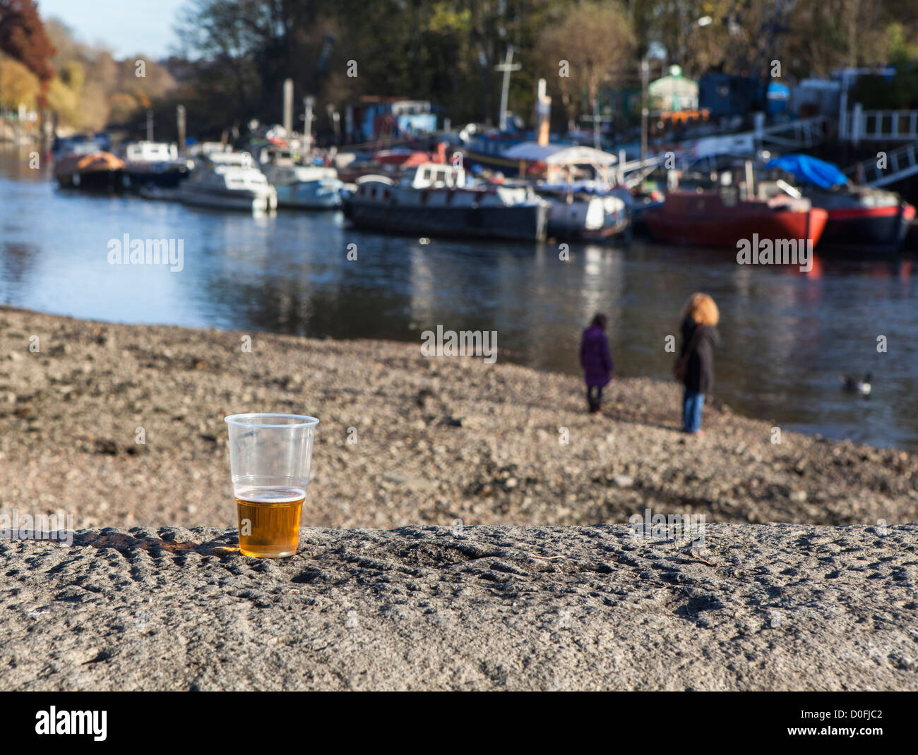 Un verre de bière à moitié vide est supprimé et les gens marchent sur les lit de la rivière Thames, à marée basse Banque D'Images
