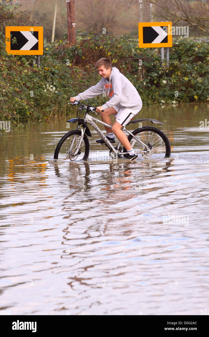 Street, Somerset, England, UK - 25 novembre 2012. Les routes secondaires entre Glastonbury et Street près de la rivière Brue a été inondée - jeunes ont l'occasion d'avoir du plaisir dans les inondations. Banque D'Images