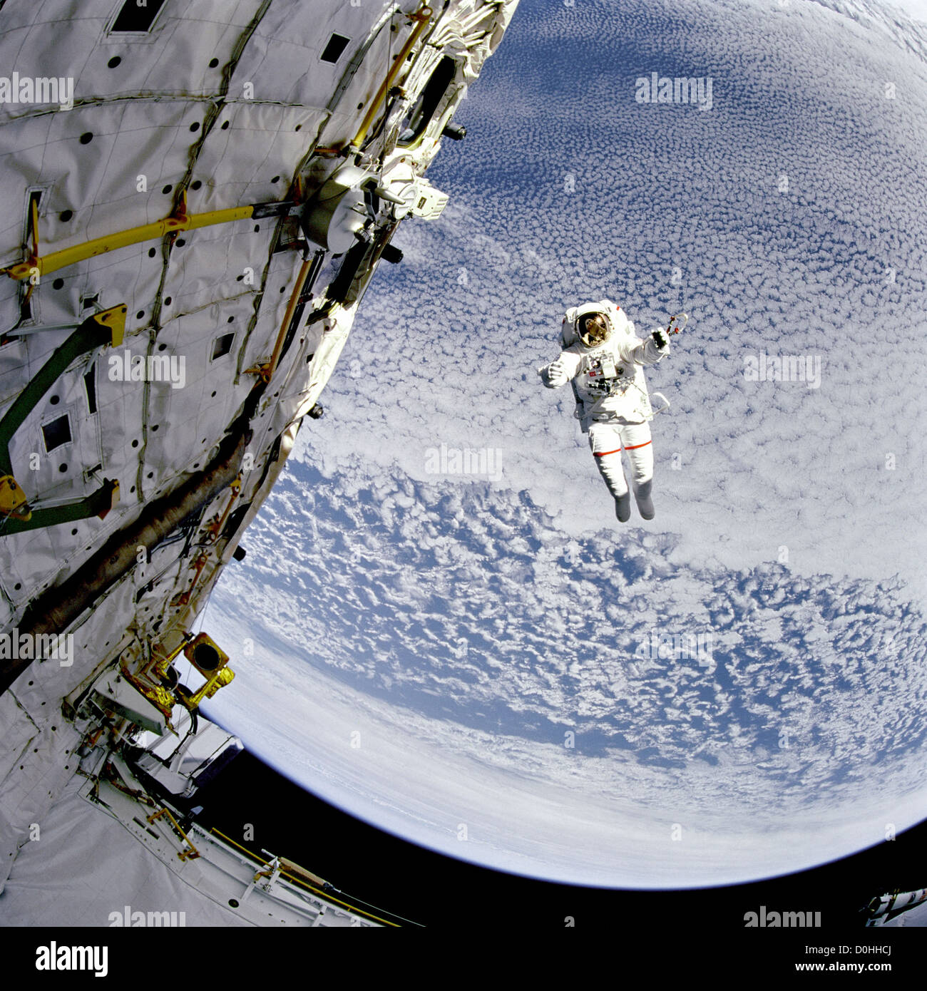 Backdropped contre le bleu et blanc de 130 milles de la terre ci-dessous, l'astronaute Mark C. Lee teste la nouvelle aide simplifiée pour EV Banque D'Images
