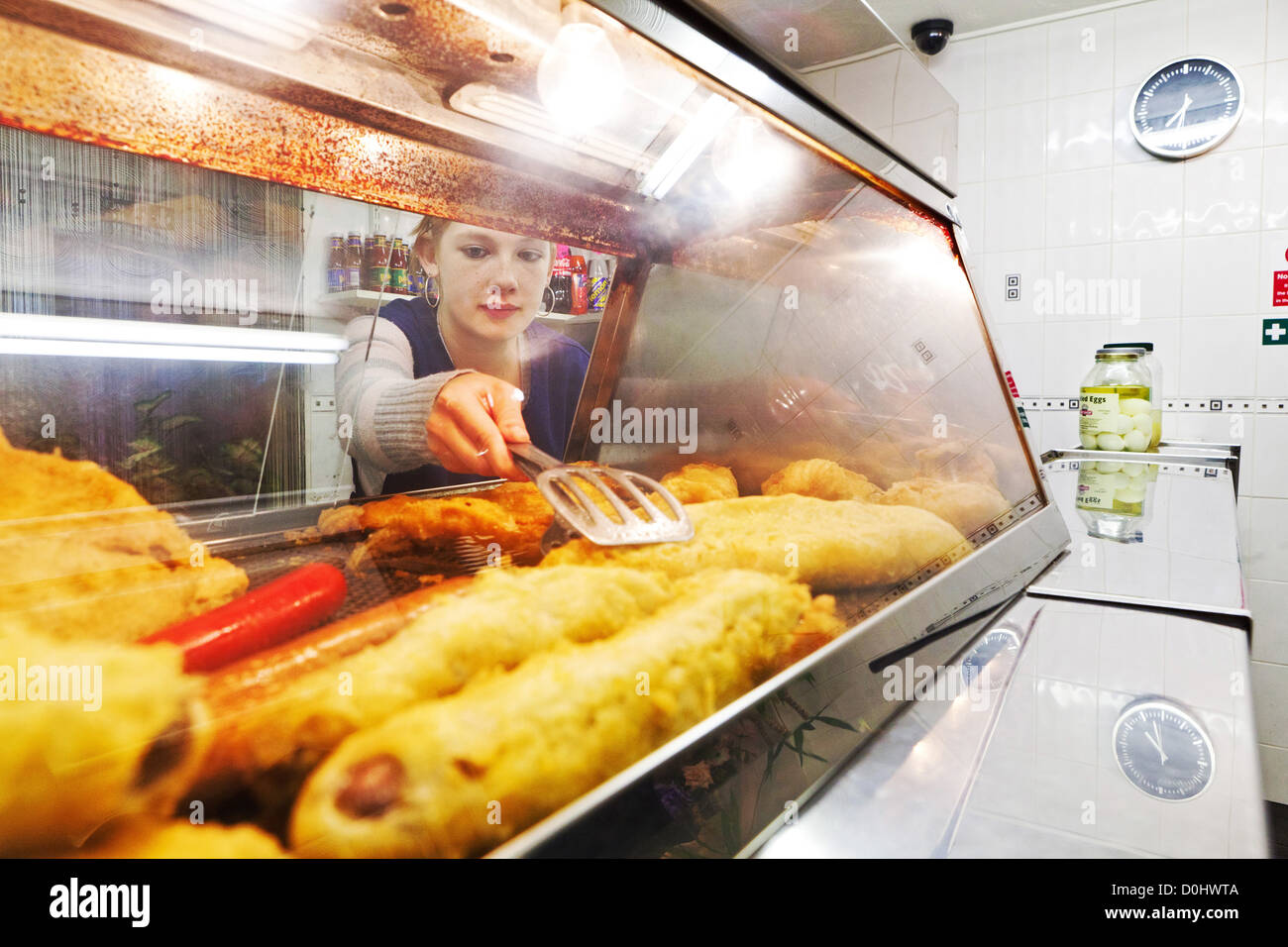 Une fille atteint dans une assiette chaude à servir le poisson et frites. Banque D'Images