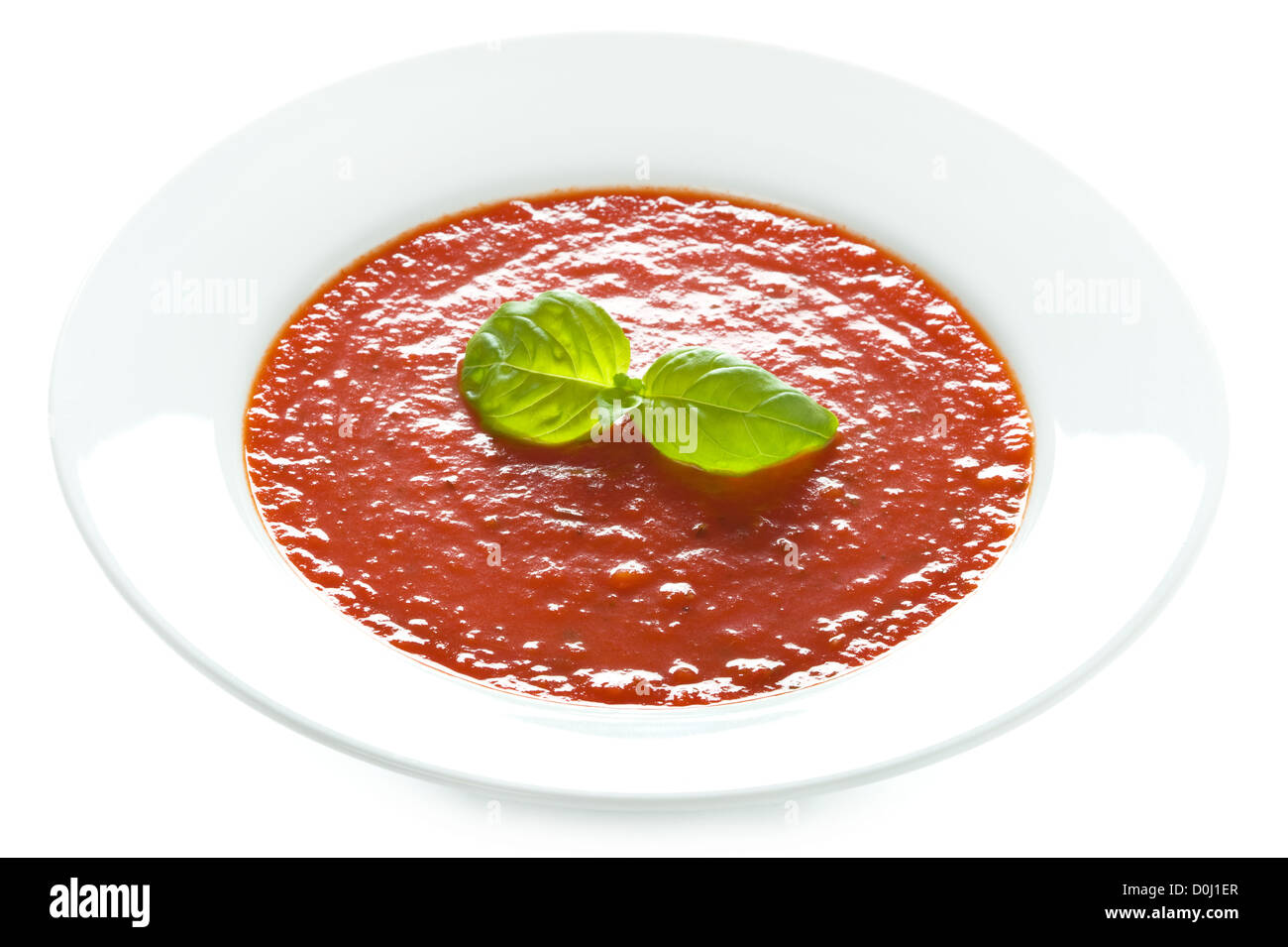Soupe de tomate au basilic garniture dans un bol blanc isolé Banque D'Images