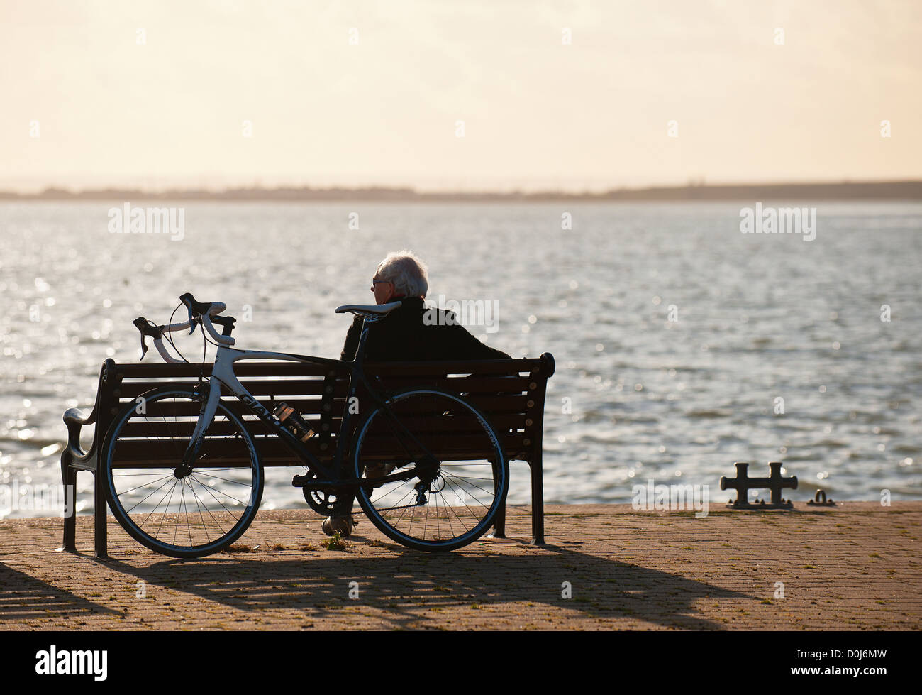 Un cycliste se reposant sur un banc avec vue sur l'estuaire de la Tamise. Banque D'Images