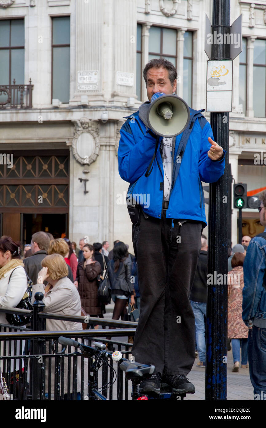 Un homme debout sur un post traitement indifférent des foules de gens dans la région de Oxford Circus. Banque D'Images