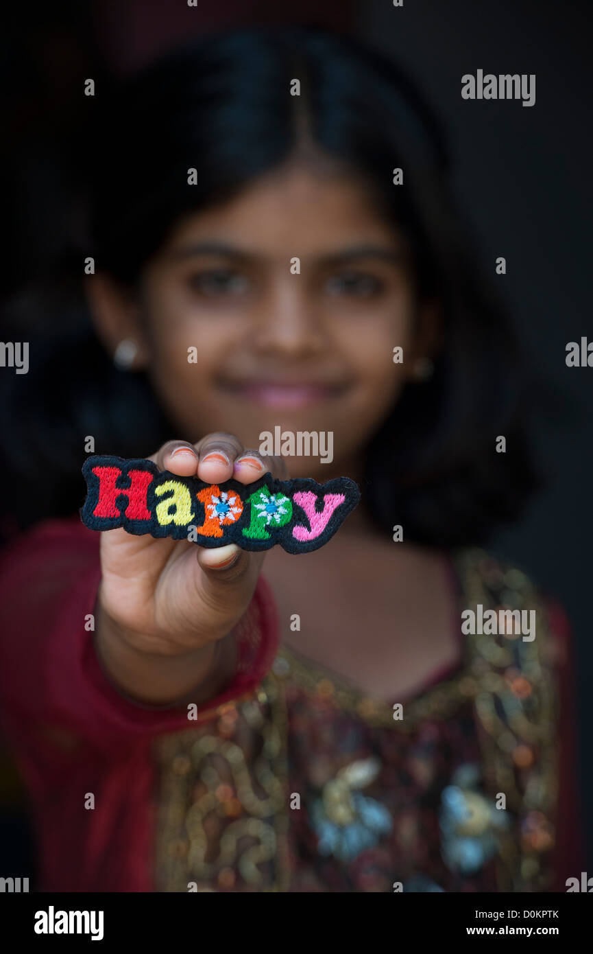 Smiling Indian girl holding a heureux patch broderie multicolore Banque D'Images