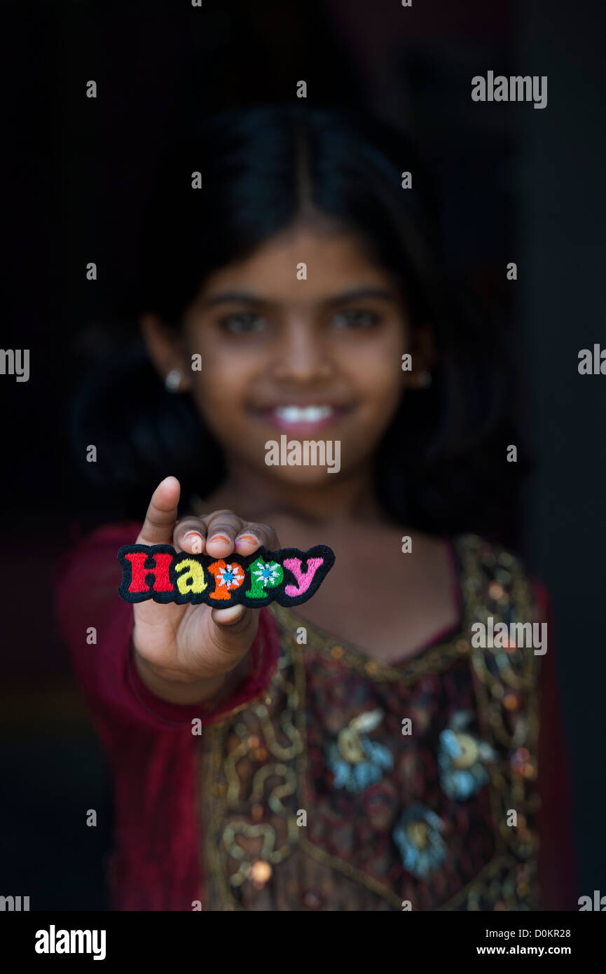 Smiling Indian girl holding a heureux patch broderie multicolore Banque D'Images