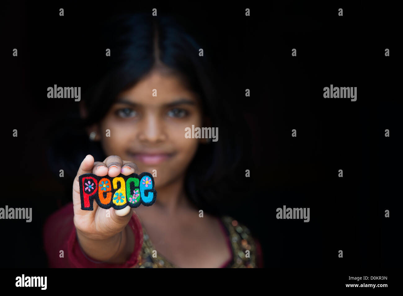 Smiling Indian girl holding a patch broderie multicolore paix Banque D'Images