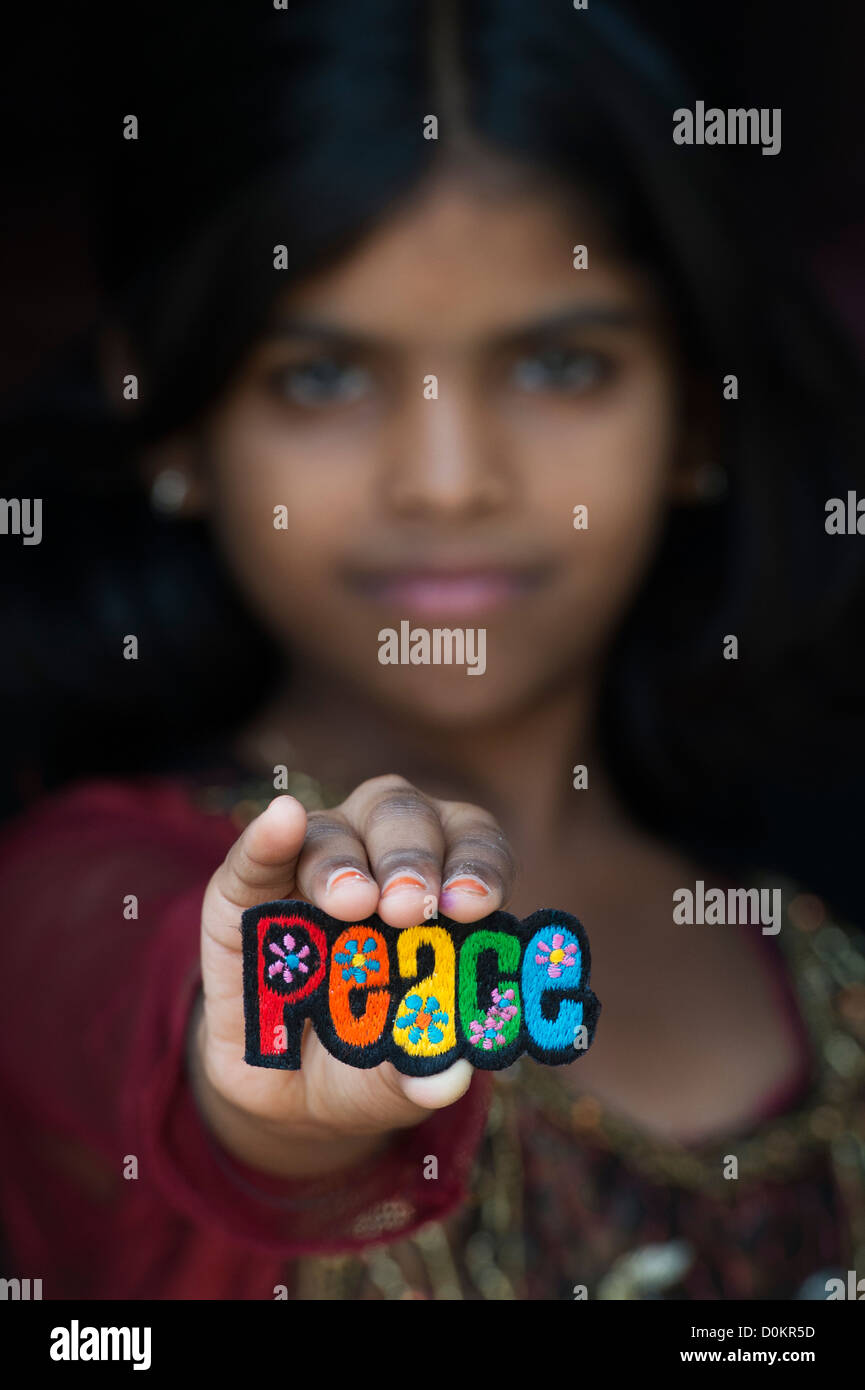 Smiling Indian girl holding a patch broderie multicolore paix Banque D'Images