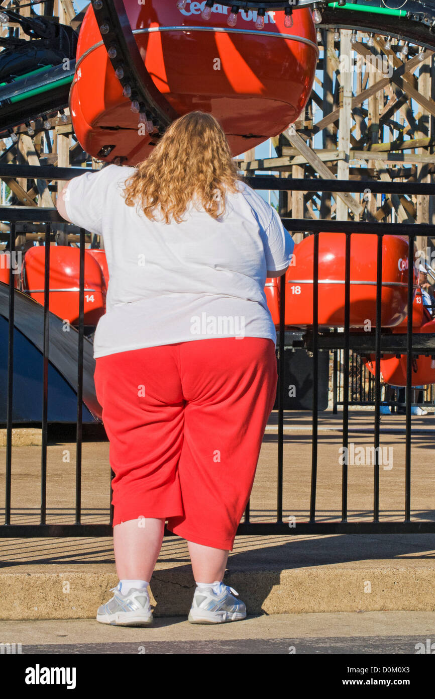 Une grande femme en rouge se distingue par un survêtement carnival ride. Banque D'Images