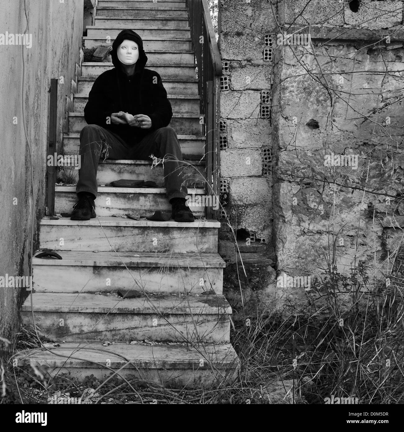 Masque à la poupée part assis sur l'escalier maison abandonnée. Noir et blanc. Banque D'Images