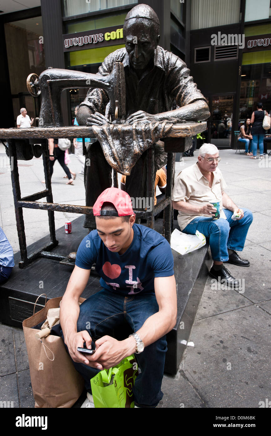 Textes d'un jeune homme en face d'une statue d'un vieil homme Manhatttan,couture Banque D'Images