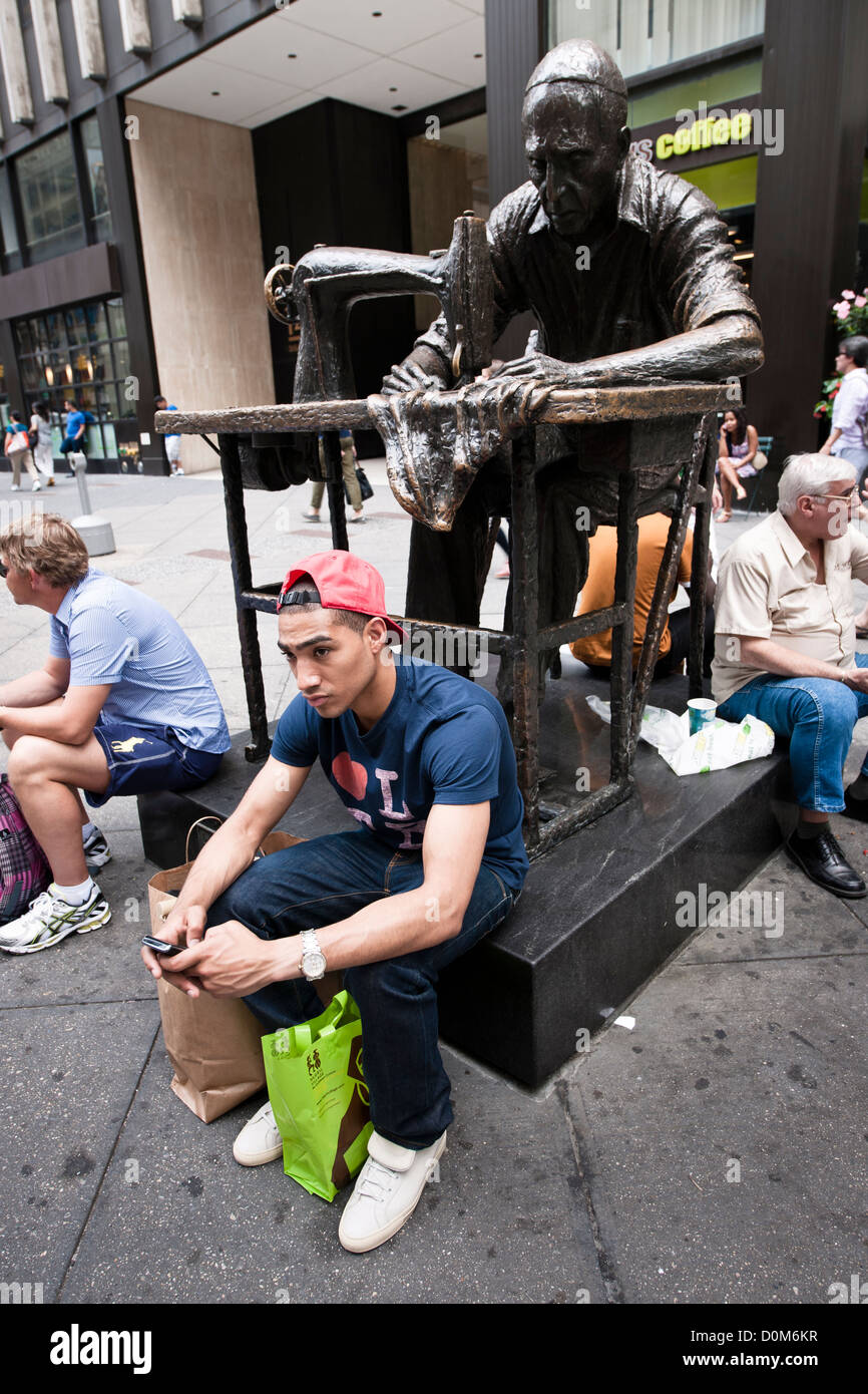 Textes d'un jeune homme en face d'une statue d'un vieil homme Manhatttan,couture Banque D'Images