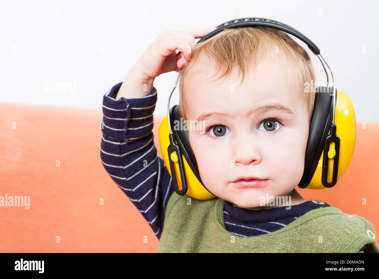 Jeune enfant sur table avec des cache-oreilles jaune Photo Stock - Alamy
