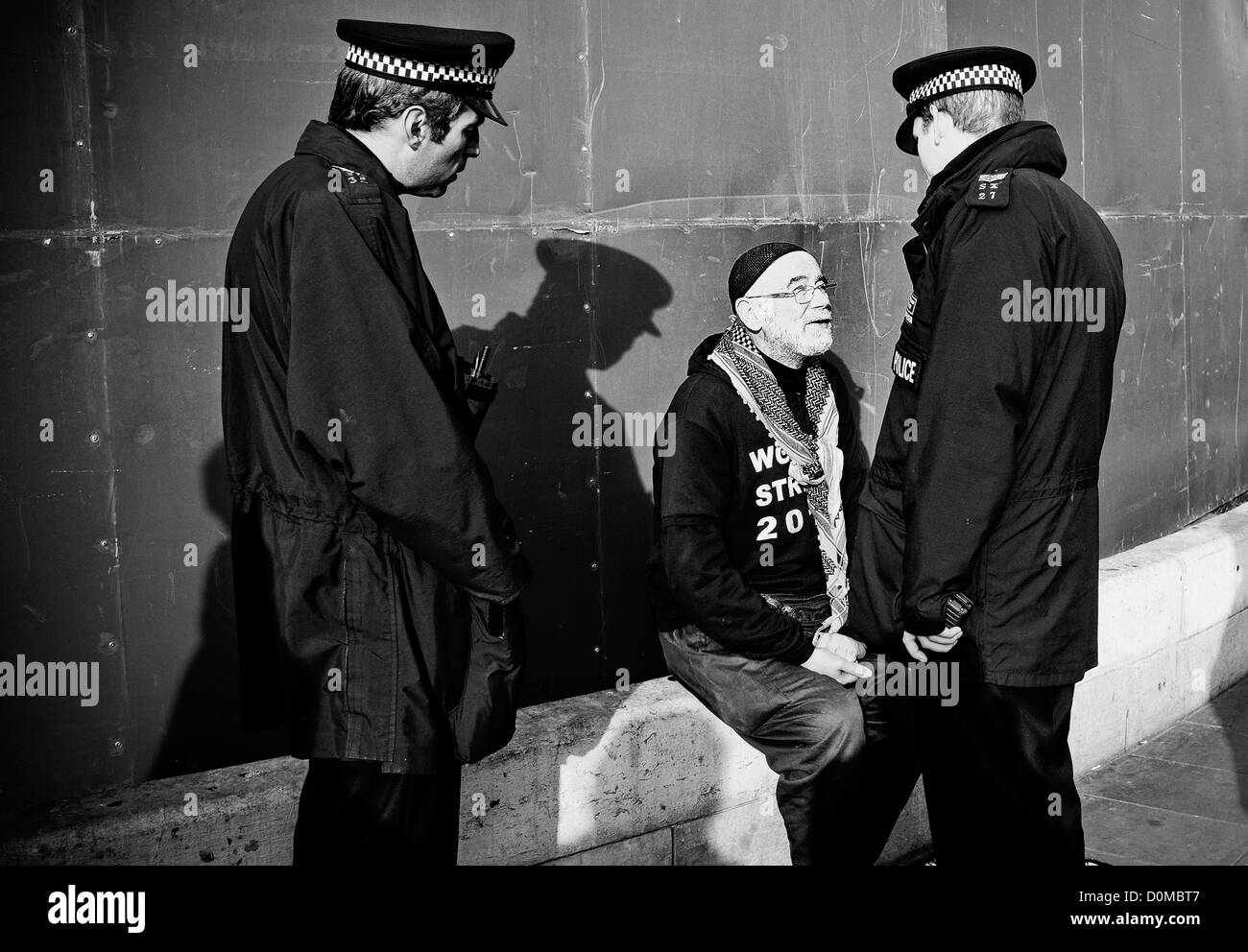 Manifestant à Trafalgar square étant parlé par 2 agents de police en uniforme Banque D'Images