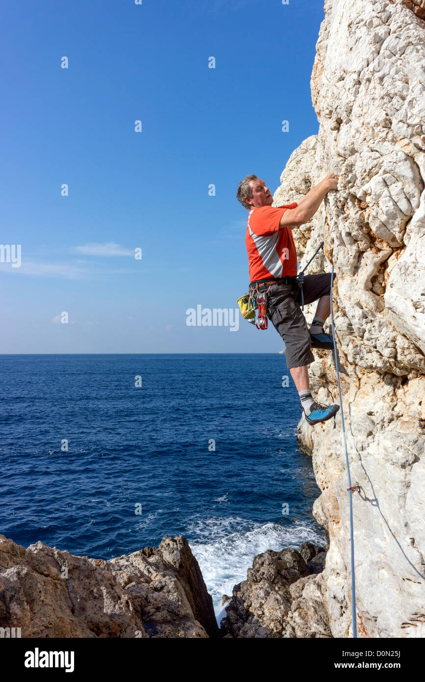 Male rock climber wearing red sur falaise, Kalymnos, Grèce Banque D'Images