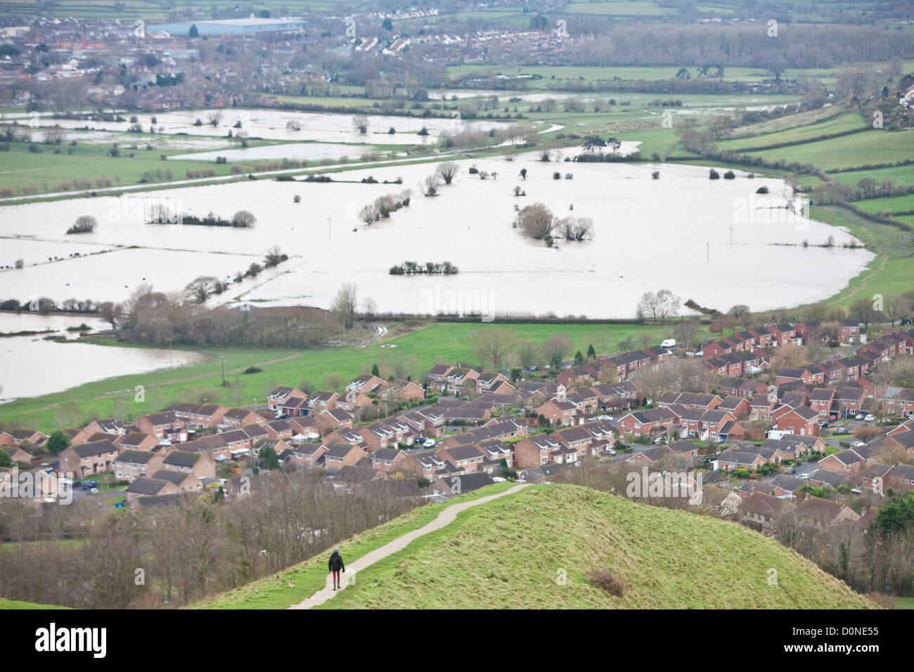Glastonbury, United Kingdom-November 27e. Chien femelle walker sur chemin sur Glastonbury Tor.l'eau d'inondation dans les champs entourant le Tor de Glastonbury sur Somerset Levels. Photographie prise à partir des Tor de Glastonbury, Glastonbury, Somerset, Angleterre. Banque D'Images