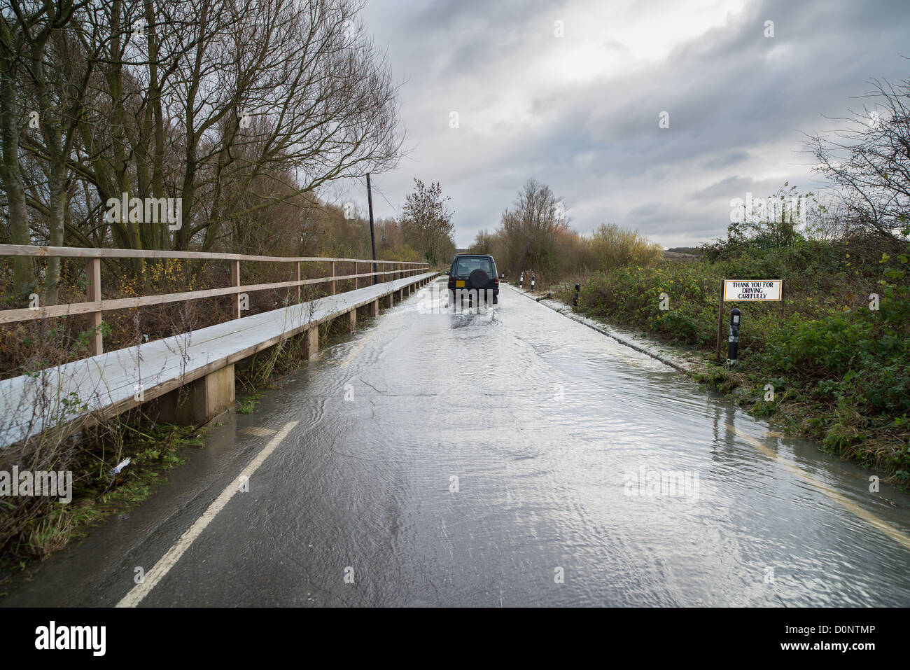 Caefully conduite sur Ringstead Rd, Northamptonshire, en novembre 2012, en raison de la rivière Nene déborde de ses rives. Banque D'Images