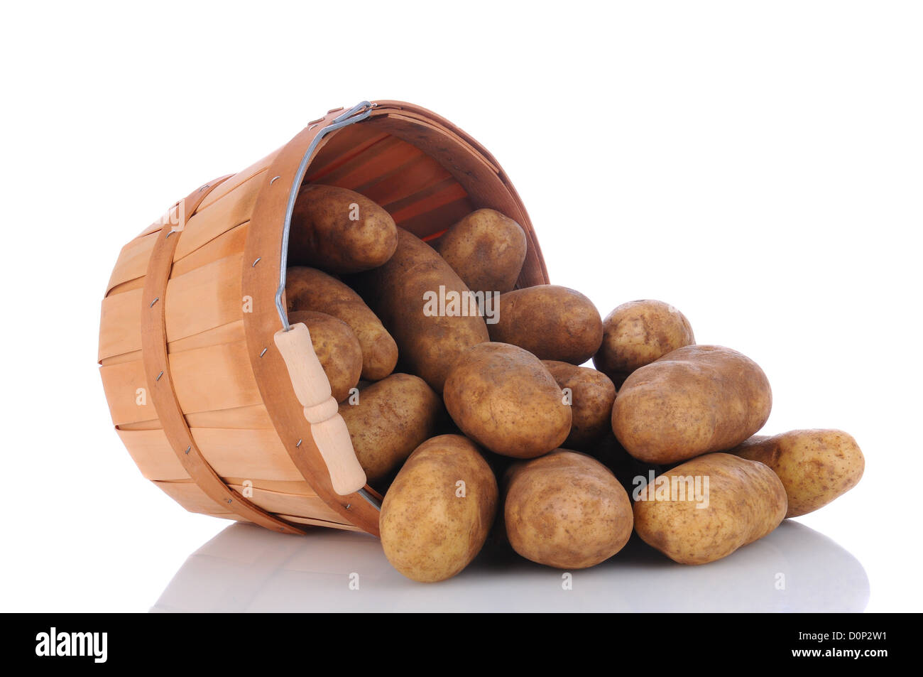 Un panier plein de pommes de terre roussâtres sur le côté sur une surface blanche avec réflexion. Format horizontal. Banque D'Images