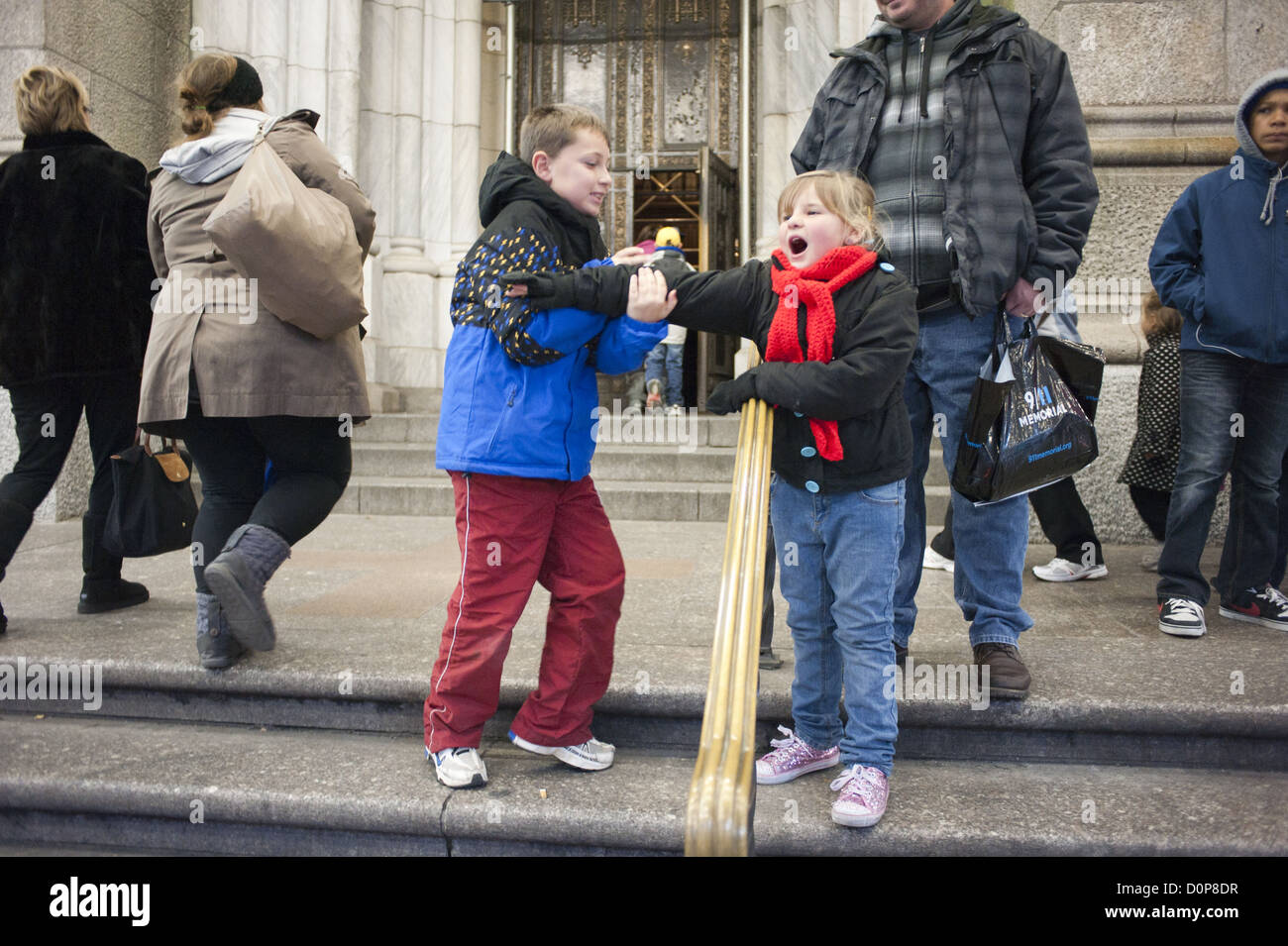 Garçon bousculades avec sa jeune sœur sur les marches de la cathédrale Saint Patrick sur la Cinquième Avenue à New York City, 2012. Banque D'Images