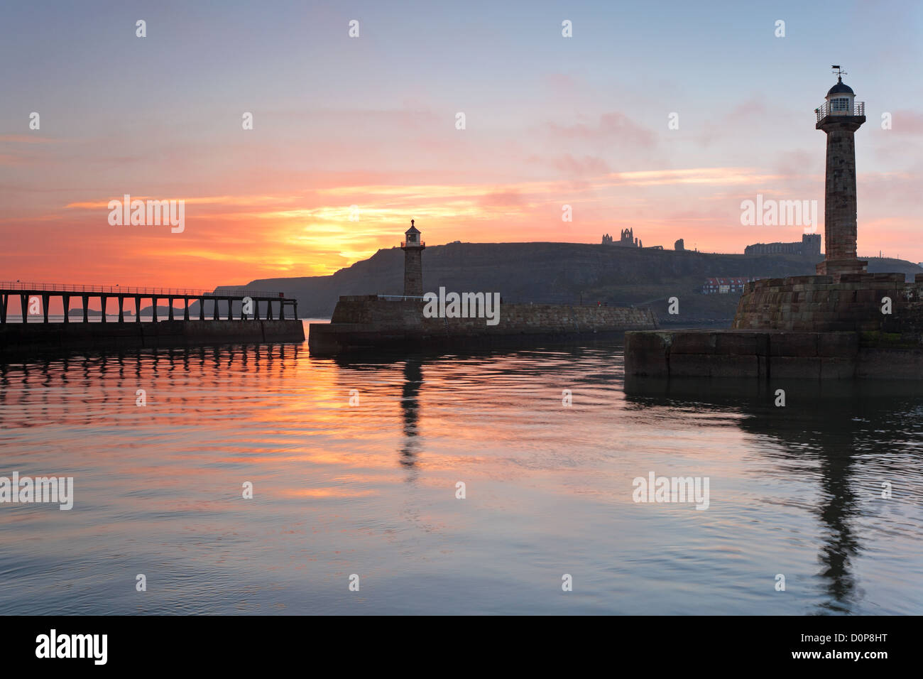 Le port de Whitby dans le Yorkshire du Nord, Angleterre, avec le lever du soleil illuminant le ciel. Banque D'Images