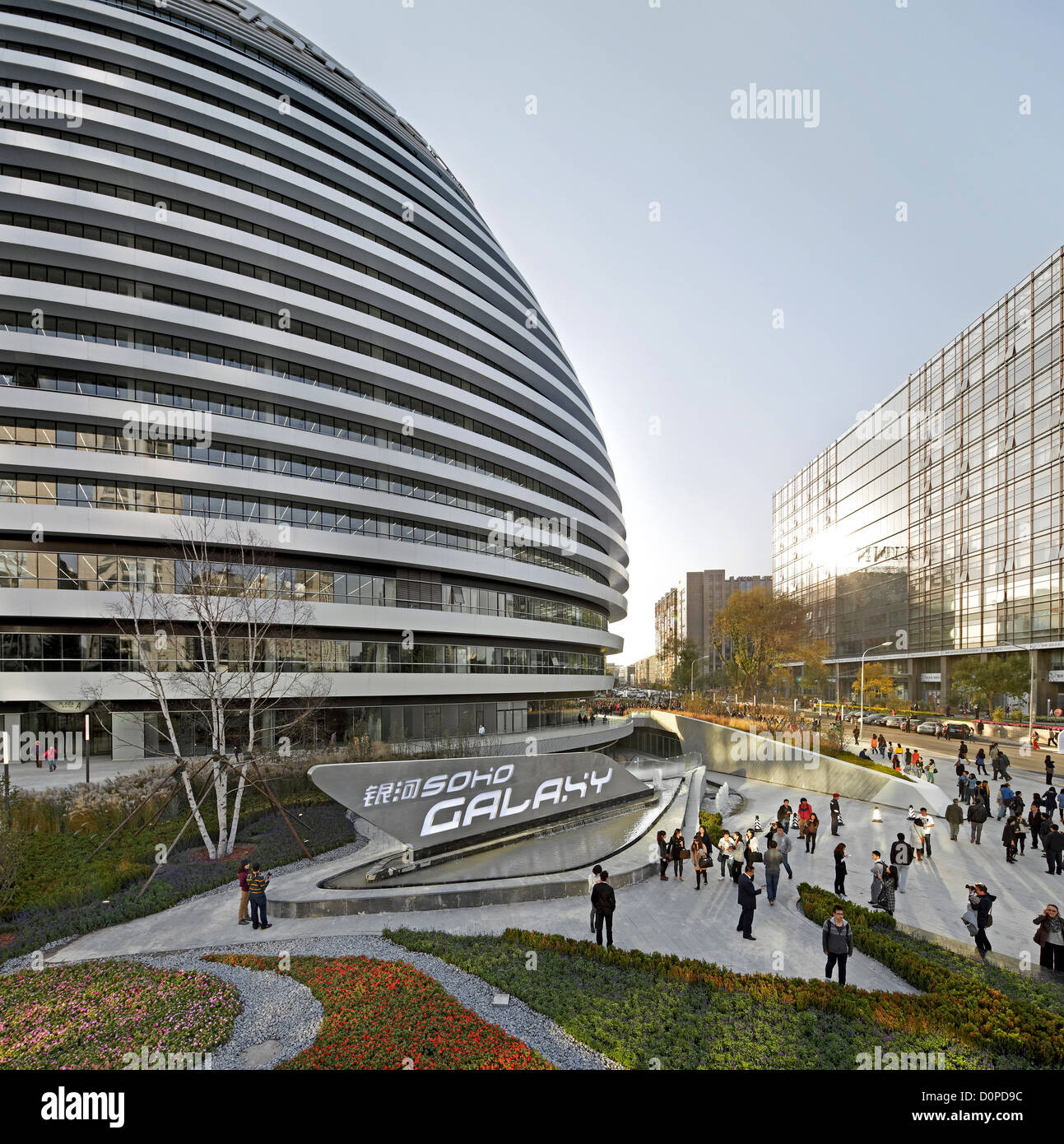Galaxy Soho, Beijing, Chine. Architecte : Zaha Hadid Architects, 2012. Scène de rue bondée avec Dome. Banque D'Images