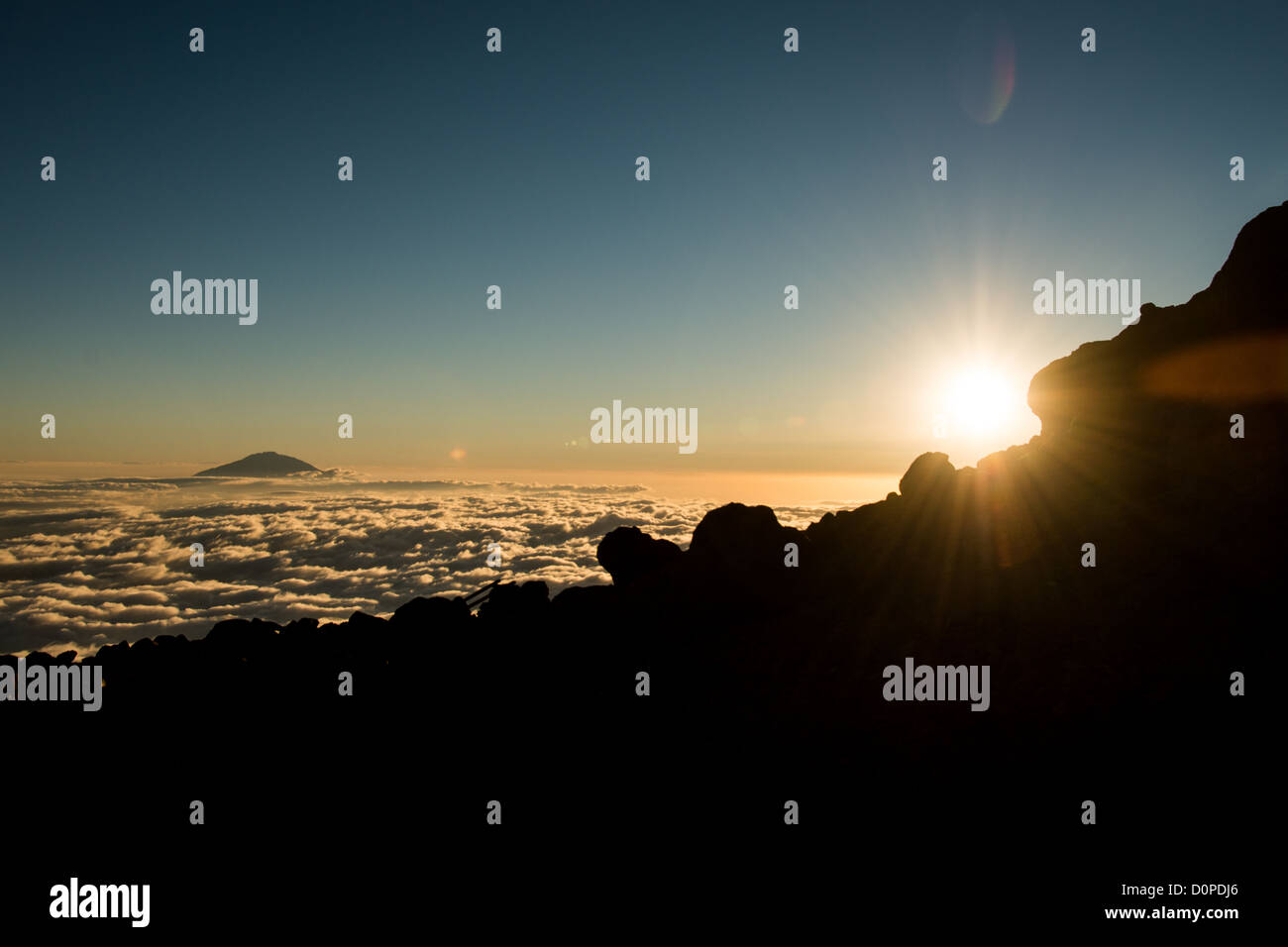 Le mont Kilimandjaro, Tanzanie - Le sommet du Mont Meru pokes à travers les nuages tandis que le soleil se couche à l'horizon comme vu à partir de la flèche située sur le glacier du Kilimandjaro Lemosho Route. Banque D'Images