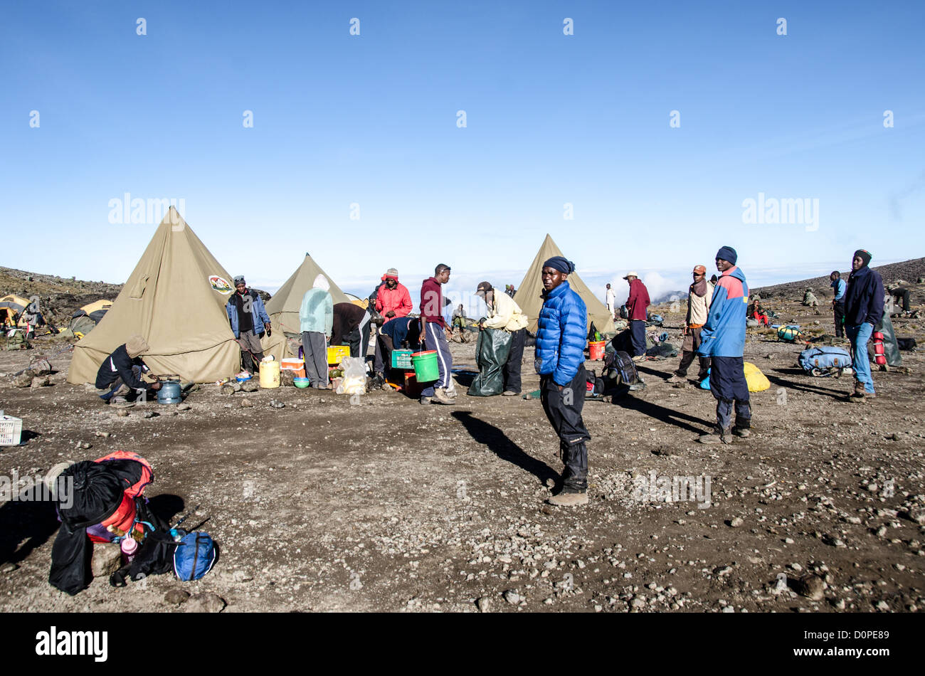 MONT KILIMANDJARO, Tanzanie — les porteurs se préparent à empaqueter le camp de Moir Hut Camp, situé à 13 660 pieds sur la route Lemosho du Mont Kilimandjaro. La route Lemosho est l'une des nombreuses routes d'escalade établies sur le plus haut sommet d'Afrique, approchant la montagne par l'ouest. Moir Hut Camp sert d'étape d'acclimatation clé pour les grimpeurs qui montent vers le sommet du Kilimandjaro à 19 341 pieds. Les porteurs jouent un rôle essentiel dans les expéditions du Kilimandjaro, transportant du matériel et des fournitures pour les groupes d'escalade. La route de Lemosho est connue pour son approche pittoresque et prend généralement sept à huit jours pour comp Banque D'Images