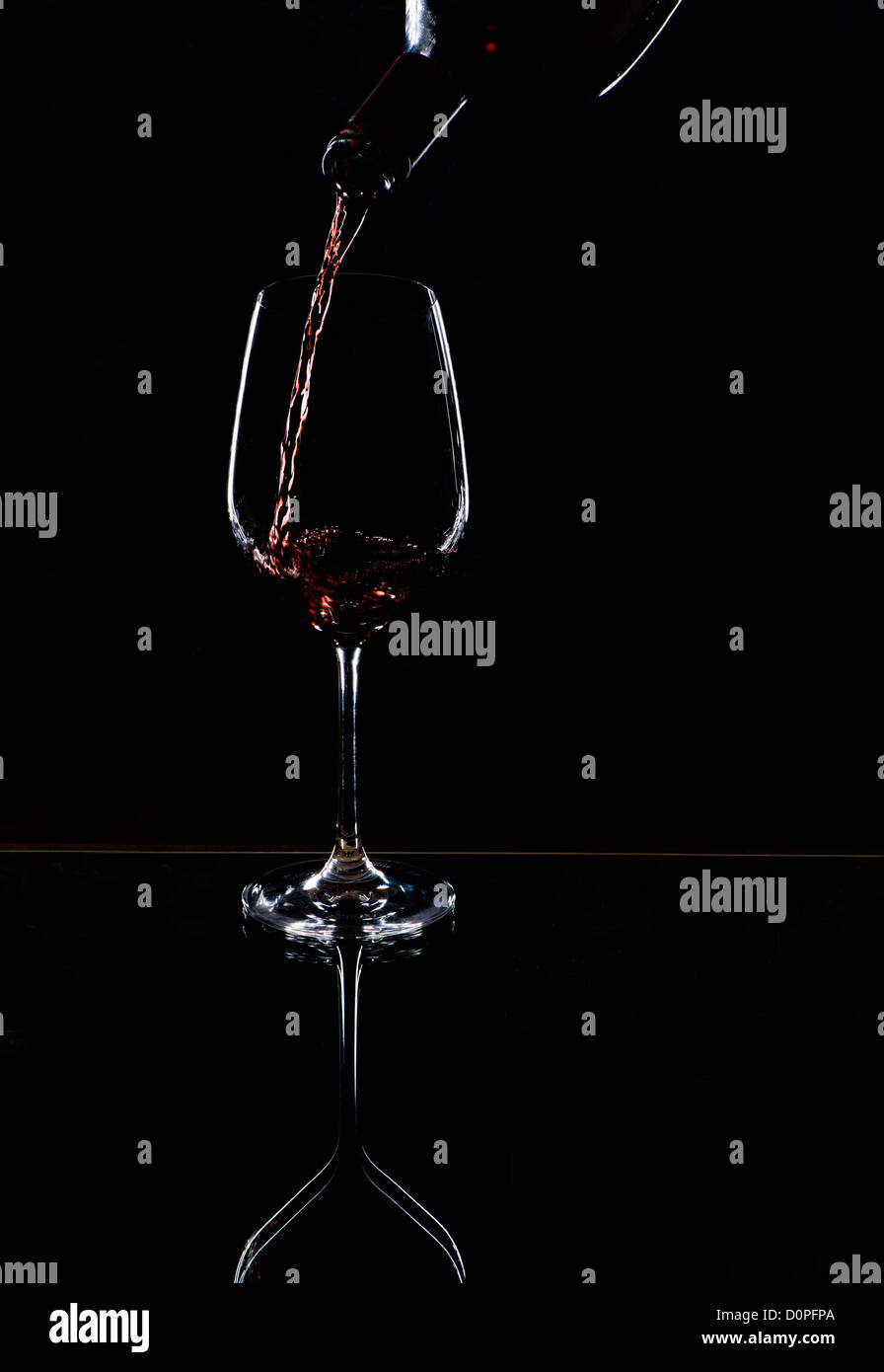 Verser le vin rouge dans le verre, contour noir fond Banque D'Images