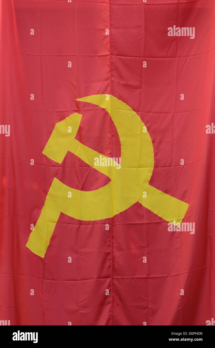 Drapeau communiste symbole du marteau et de la faucille Vientiane Laos // VIENTIANE, Laos — Un drapeau communiste arborant le symbole du marteau et de la faucille, emblème internationalement reconnu du communisme, est montré dans la capitale du Laos. Le marteau représente la classe ouvrière industrielle ou le prolétariat, tandis que la faucille symbolise la paysannerie agricole ou les travailleurs ruraux. Ce symbole emblématique a d'abord été adopté par l'Union soviétique et par la suite est devenu associé aux mouvements communistes dans le monde entier. La République démocratique populaire lao, créée en 1975, est gouvernée par le Parti révolutionnaire populaire lao, wh Banque D'Images