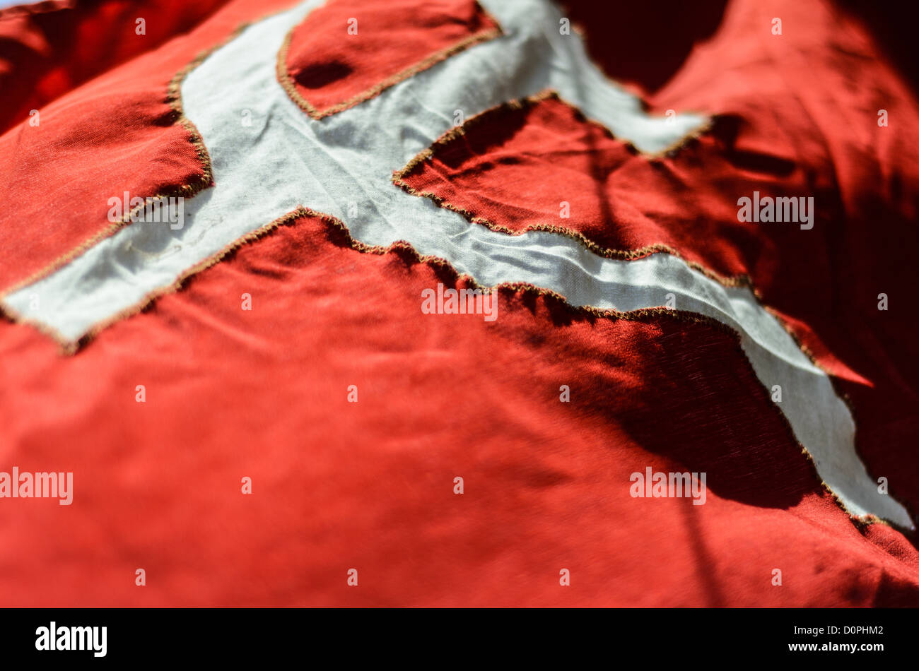 Drapeau communiste marteau et faucille Phonsavan Laos // PHONSAVAN, Laos — Un drapeau communiste bien usé, avec l'emblème emblématique du marteau et de la faucille, vole à Phonsavan, Laos. Ce symbole représente la solidarité des travailleurs industriels et agricoles sous l'idéologie communiste. Le fond rouge du drapeau signifie la révolution et l'engagement pour le socialisme. Banque D'Images