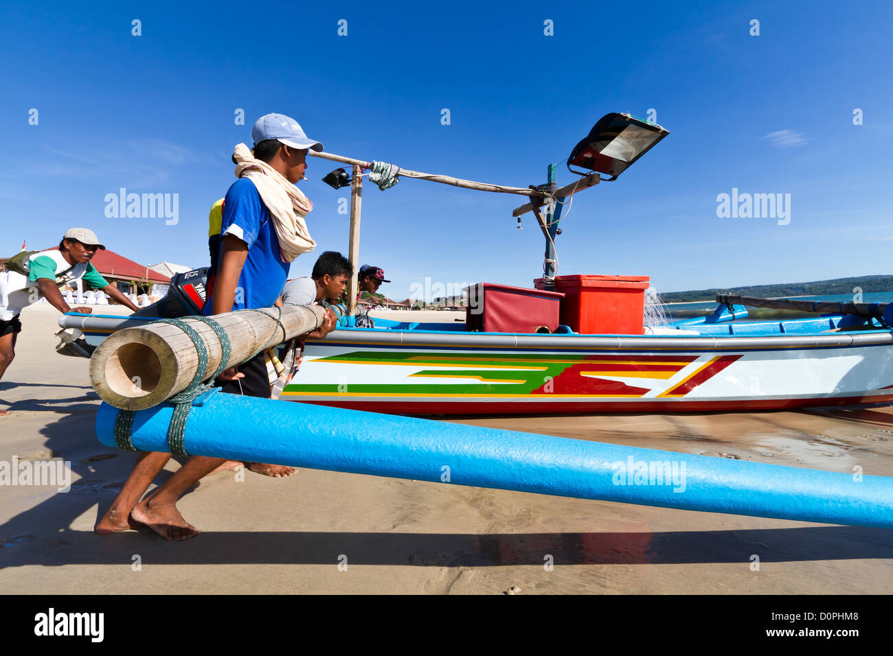 Les pêcheurs musulmans poussant leur bateau jusqu'à l'océan sur la plage de Jimbaran en Bali, Indonésie Banque D'Images