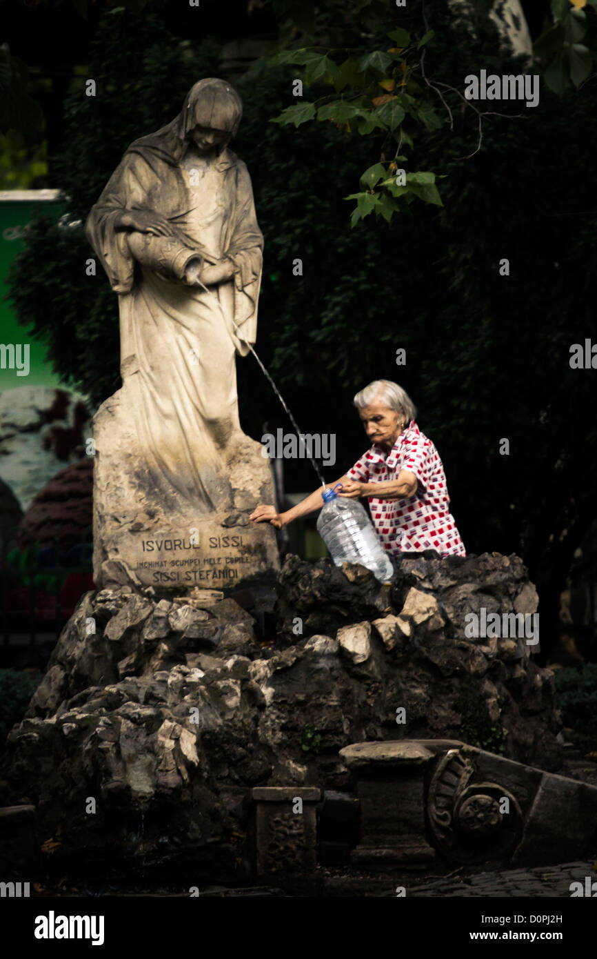 Une vieille femme sa bouteille de remplissage avec de l'eau d'une fontaine  publique Photo Stock - Alamy