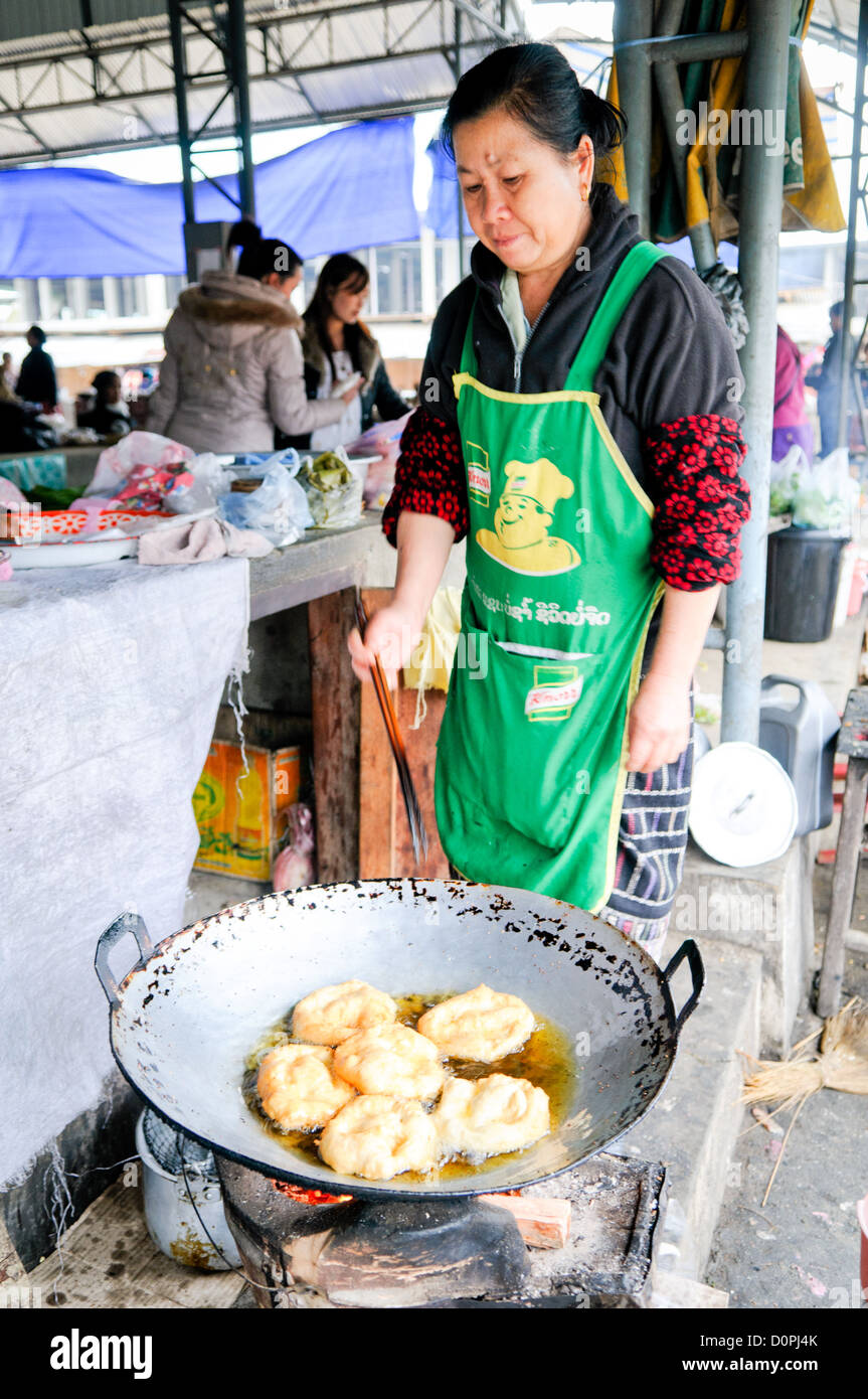 SAM NEUA, Laos - une femme cuisiniers pâte frite dans un grand wok au marché du matin dans la région de Sam Neua (également orthographié Samneua, Xamneua et Xam Neua) dans le nord-est du Laos. Banque D'Images