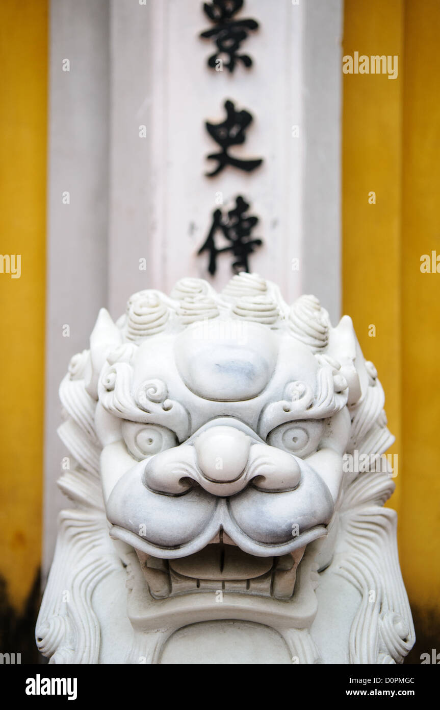 HANOI, Vietnam — des lions de marbre blanc richement sculptés gardent l'entrée d'une porte à la pagode One Pillar à côté du musée Ho Chi Minh dans le quartier Da Binh de Hanoi, Vietnam. Caractères vietnamiens en arrière-plan. Banque D'Images