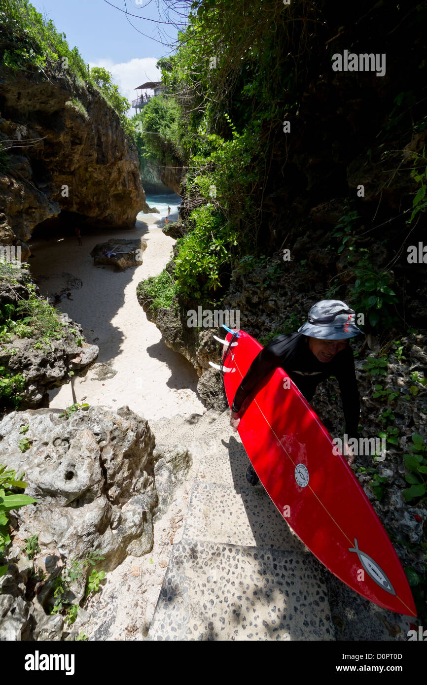 Surfer de grimper le chemin de la mer à Suluban Beach à Bali, Indonésie Banque D'Images