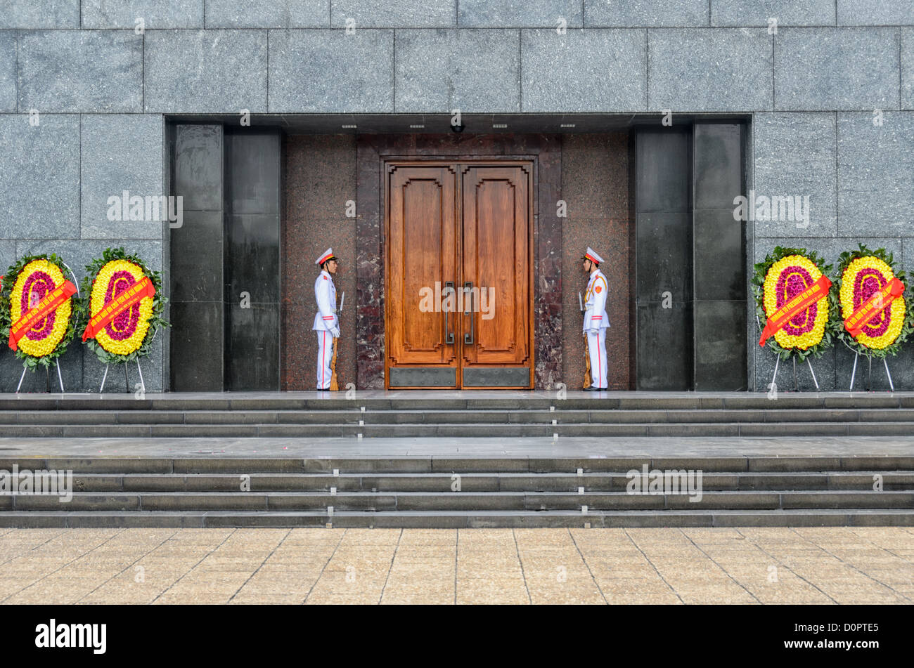 Gardes du Mausolée de Ho Chi Minh Hanoi Vietnam // HANOI, Vietnam — des gardes en uniformes de cérémonie blancs se tiennent au Mausolée de Ho Chi Minh, le lieu de repos final du leader révolutionnaire du Vietnam et premier président. La structure en granit, achevée en 1975, abrite le corps préservé de Hô Chi Minh, qui a dirigé le mouvement d'indépendance du Vietnam contre la domination coloniale française et plus tard contre les forces américaines pendant la guerre du Vietnam. Situé sur la place Ba Dinh dans le centre de Hanoi, le mausolée est l'un des monuments nationaux les plus importants du Vietnam. Le site attire des milliers de visiteurs chaque année qui Banque D'Images