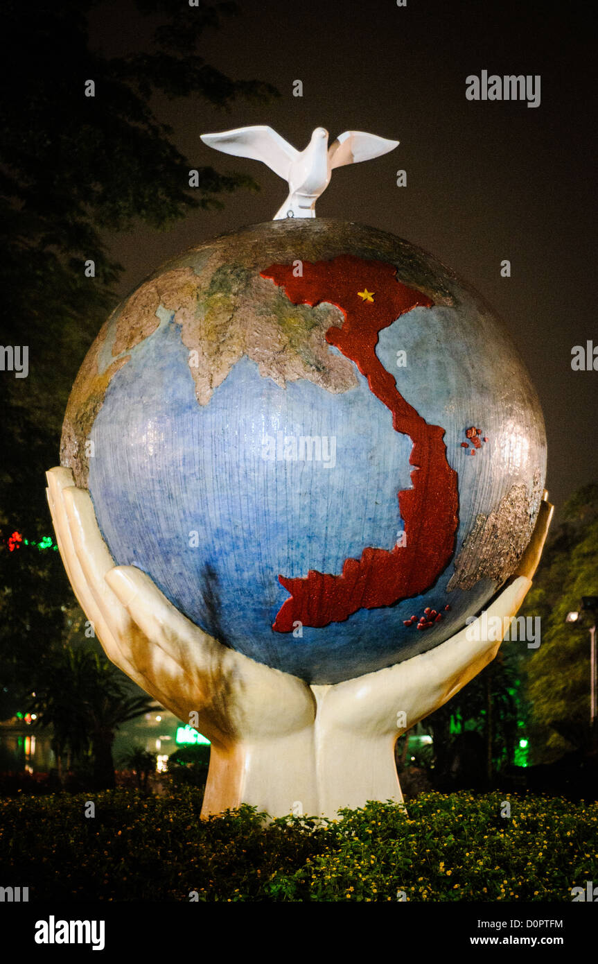 Hope and Love for Peace sculpture Hanoi Vietnam // HANOI, Vietnam — une sculpture d'art d'un globe avec des mains et une colombe sur les rives du lac Hoan Kiem à Hanoi, Vietnam. La sculpture est intitulée « espoir et amour pour la paix ». Prise de vue nocturne. Banque D'Images