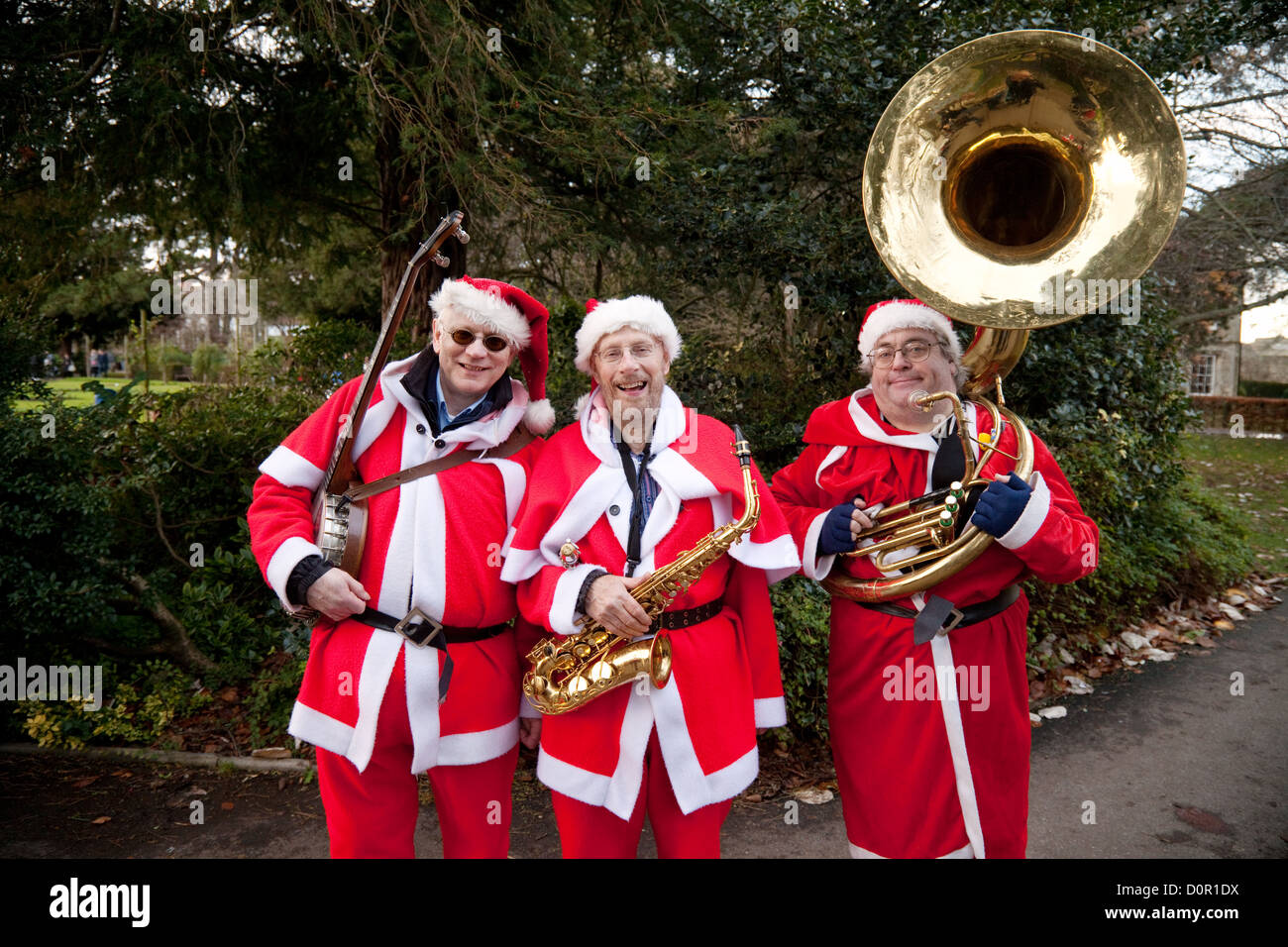 Trois hommes en costumes Père Noël à jouer de la musique à Bury St Edmunds, Suffolk Royaume-uni Marché de Noël Banque D'Images