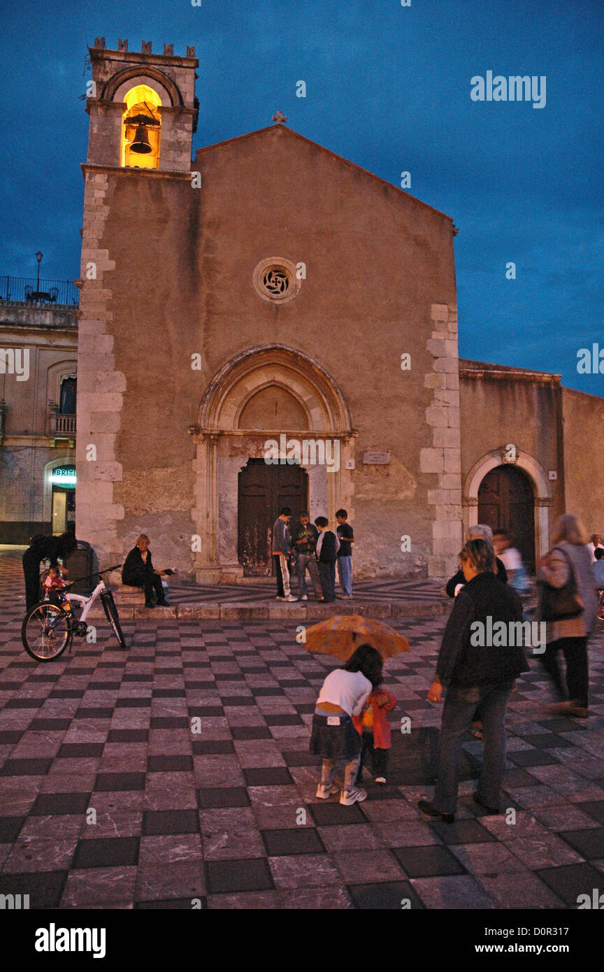 Les enfants jouent par une église à Taormina piazza -Sicile au coucher du soleil. Banque D'Images