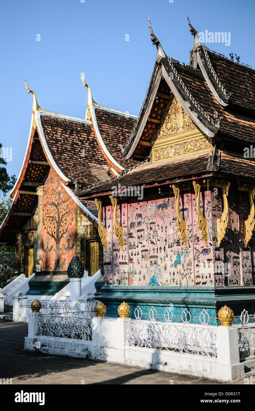 Temple de Wat Xieng Thong arbre de vie façade Luang Prabang Laos // LUANG PRABANG, Laos — Wat Xieng Thong, connu sous le nom de Temple de la Cité d'Or, affiche des éléments décoratifs ornés, y compris une grande œuvre d'art d'arbre sur sa façade. Construit vers 1560, ce complexe de temples bouddhistes se trouve à la pointe nord de la péninsule de Luang Prabang, où se rencontrent les rivières Nam Khan et Mékong. Le temple a servi de lieu aux couronnements royaux pendant le Royaume du Laos et reste l'un des sites religieux les plus importants du Laos. Wat Xieng Thong illustre l'architecture classique lao avec son low-swee distinctif Banque D'Images