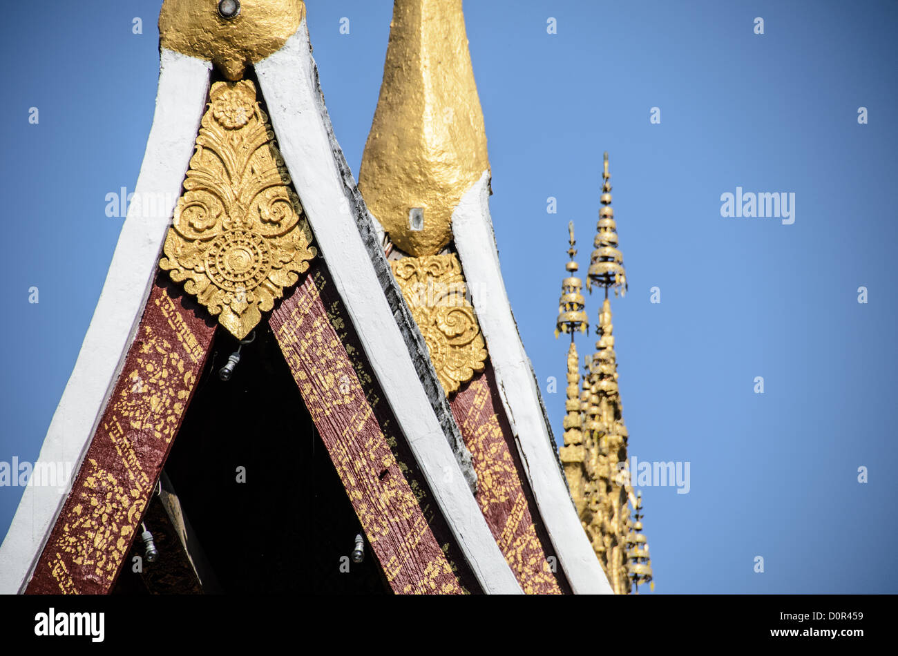 Détail du toit du temple de Wat Xieng Thong Luang Prabang Laos // LUANG PRABANG, Laos — le toit escarpé de Wat Xieng Thong (temple de la ville dorée) présente des éléments architecturaux bouddhistes traditionnels lao, notamment des chapeaux de chofah et des flèches hti. Construit vers 1560, ce temple bouddhiste emblématique se trouve à la pointe nord de la péninsule de Luang Prabang, où se rencontrent les rivières Nam Khan et Mékong. Le temple a servi de lieu aux couronnements royaux pendant le Royaume du Laos et reste l'un des sites religieux les plus importants du Laos. Wat Xieng Thong illustre l'architecture classique du temple lao avec Banque D'Images