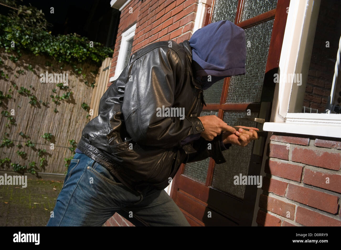 Un cambrioleur tente d'entrer dans une maison par la porte arrière Banque D'Images