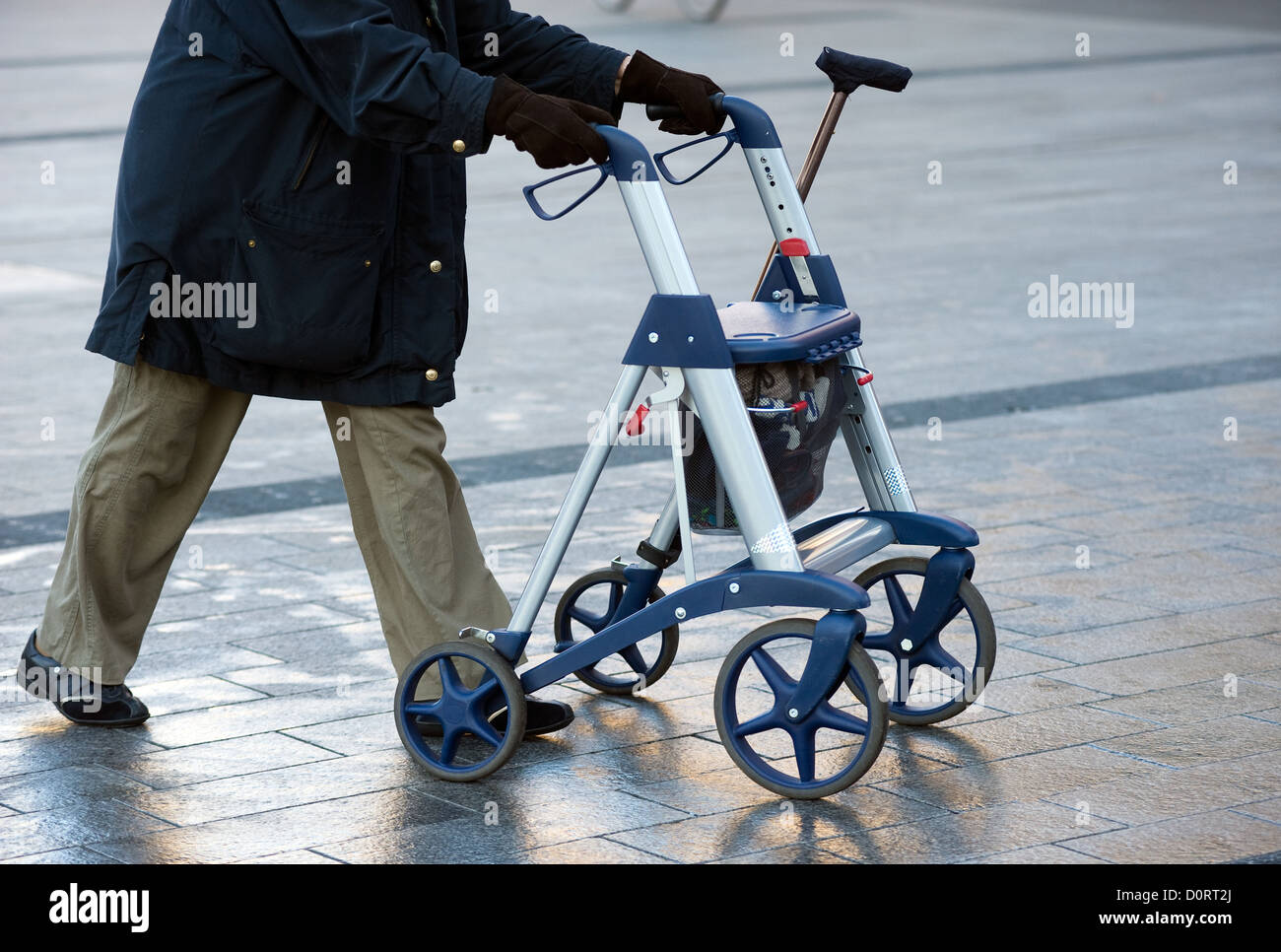 Une vieille femme marche dans la rue avec son déambulateur Banque D'Images