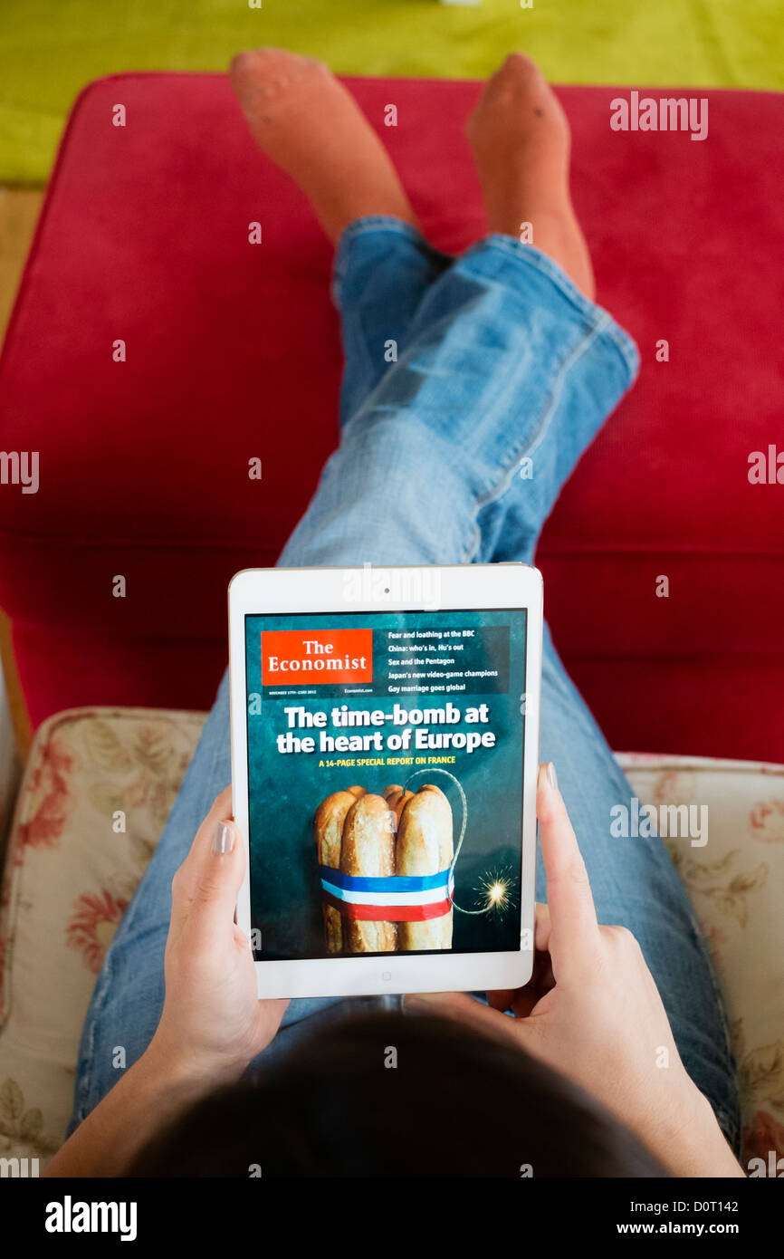 Femme à l'aide de l'application Kindle lire édition numérique de la revue The Economist sur un ordinateur tablette iPad mini Banque D'Images