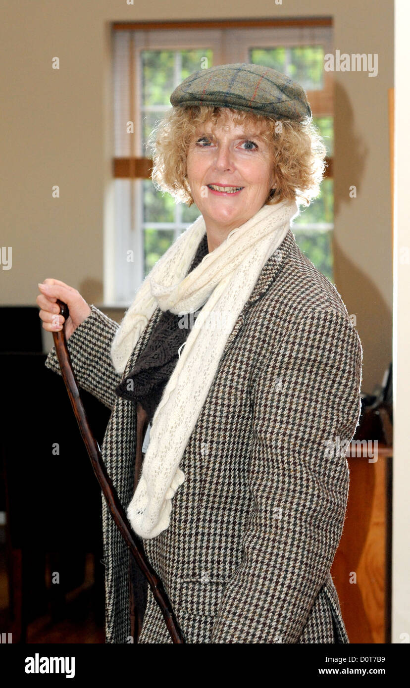 Femme d'âge moyen portant un mens Harris Tweed veste et casquette avec de vieux bâton de marche - Photo de Simon Dack Banque D'Images