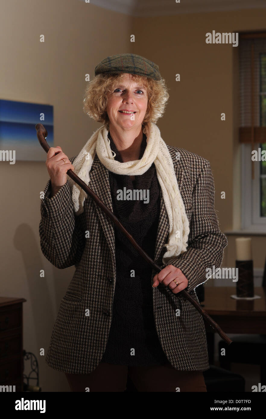 Femme d'âge moyen portant un mens Harris Tweed veste et casquette avec de vieux bâton de marche Photo prise par Simon Dack Banque D'Images